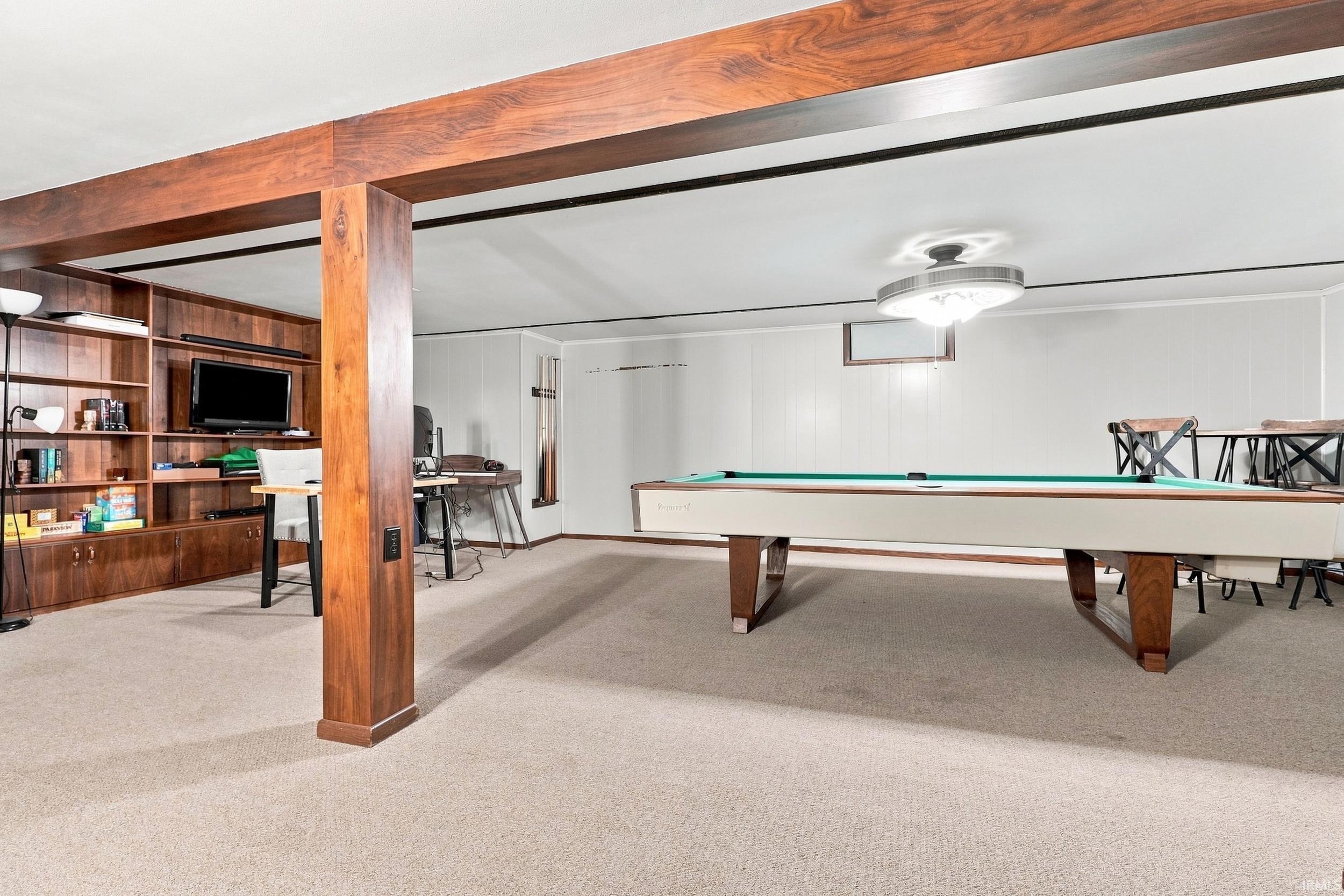 Wood-finish beam and column structure, built-in wood-finish shelving unit, wall paneling, and carpeted flooring