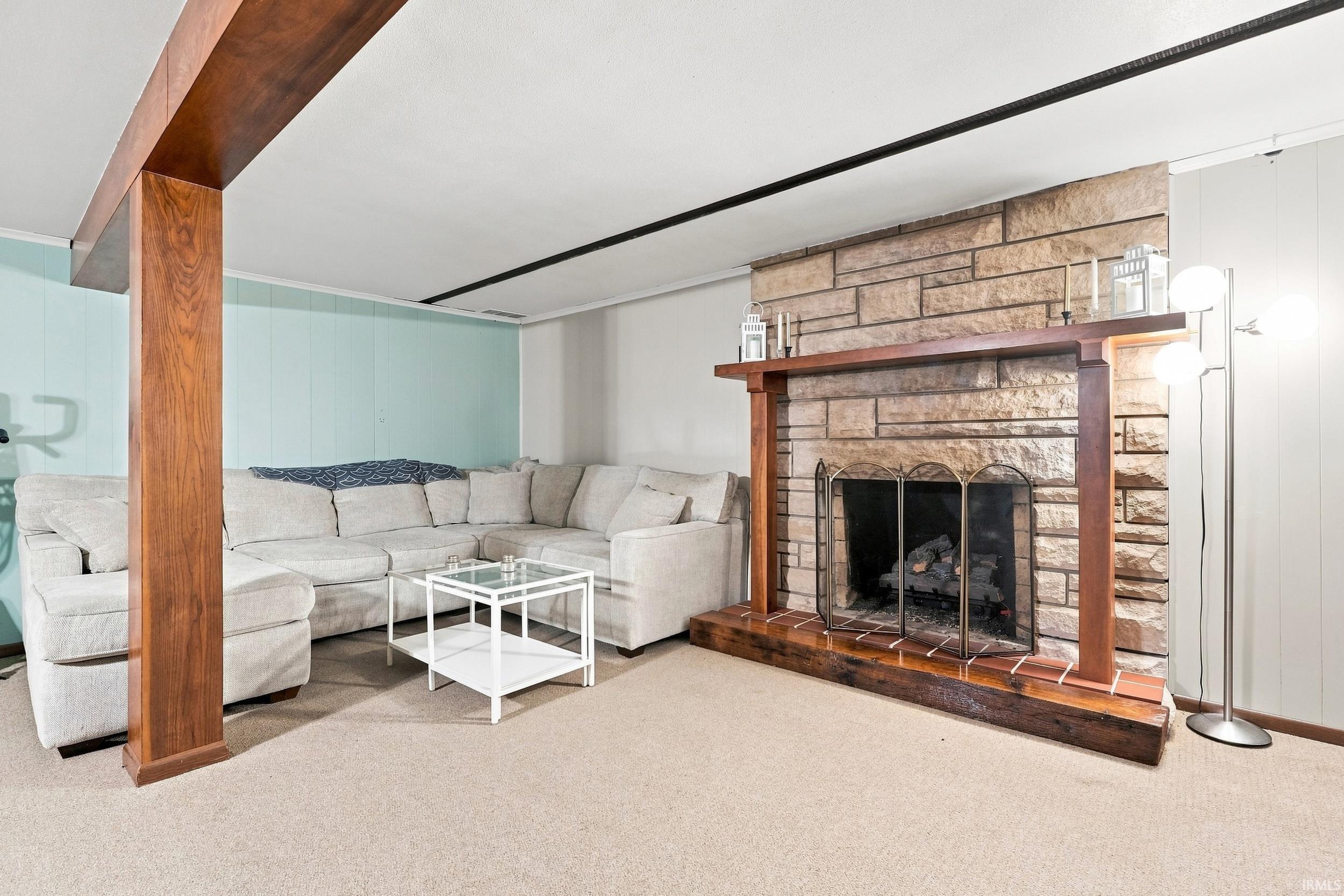 Stone fireplace with a wood-finish mantel and hearth, featuring a metal fire screen