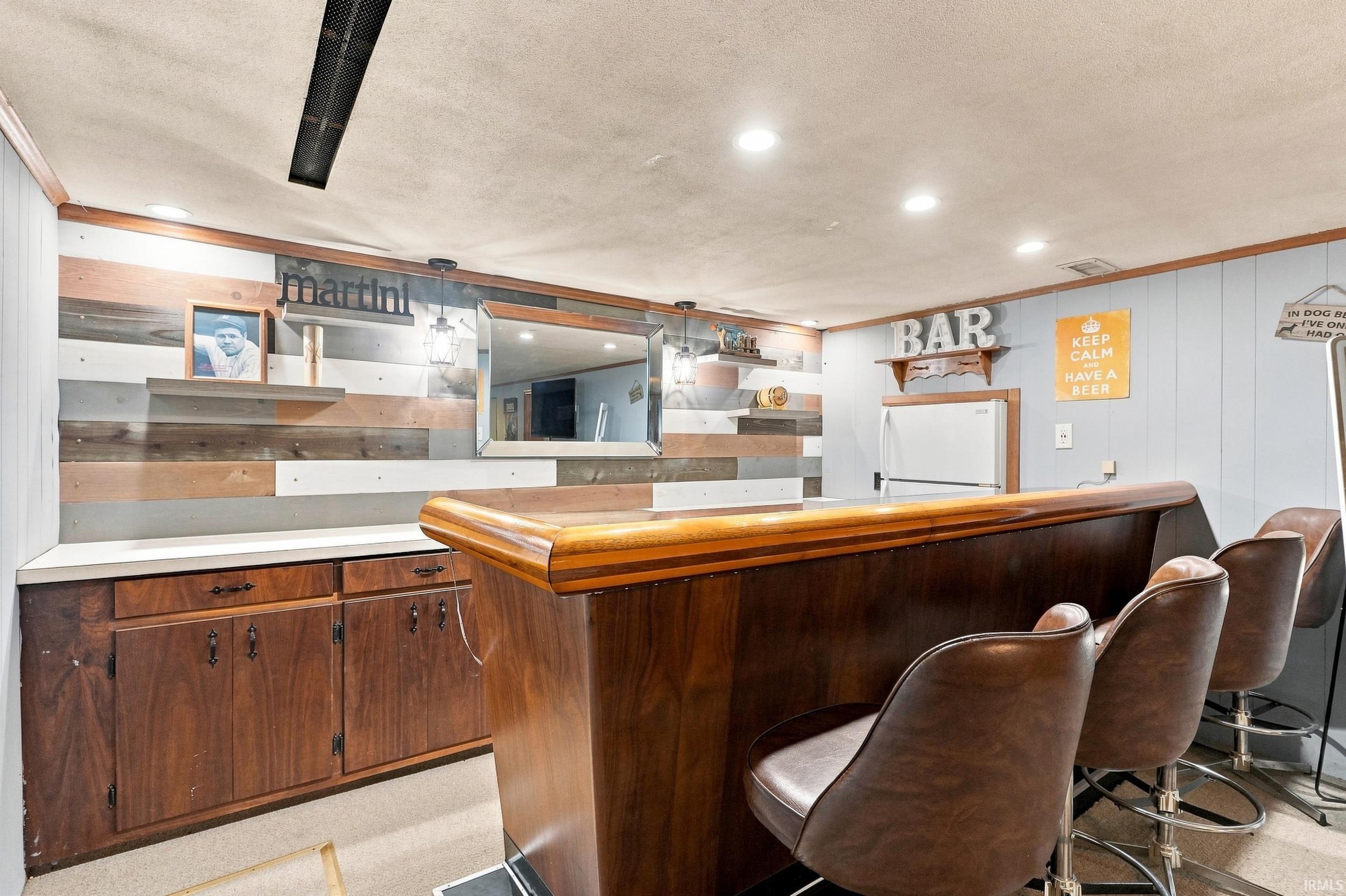 Built-in bar with a polished wood countertop, integrated wood cabinetry, and recessed lighting