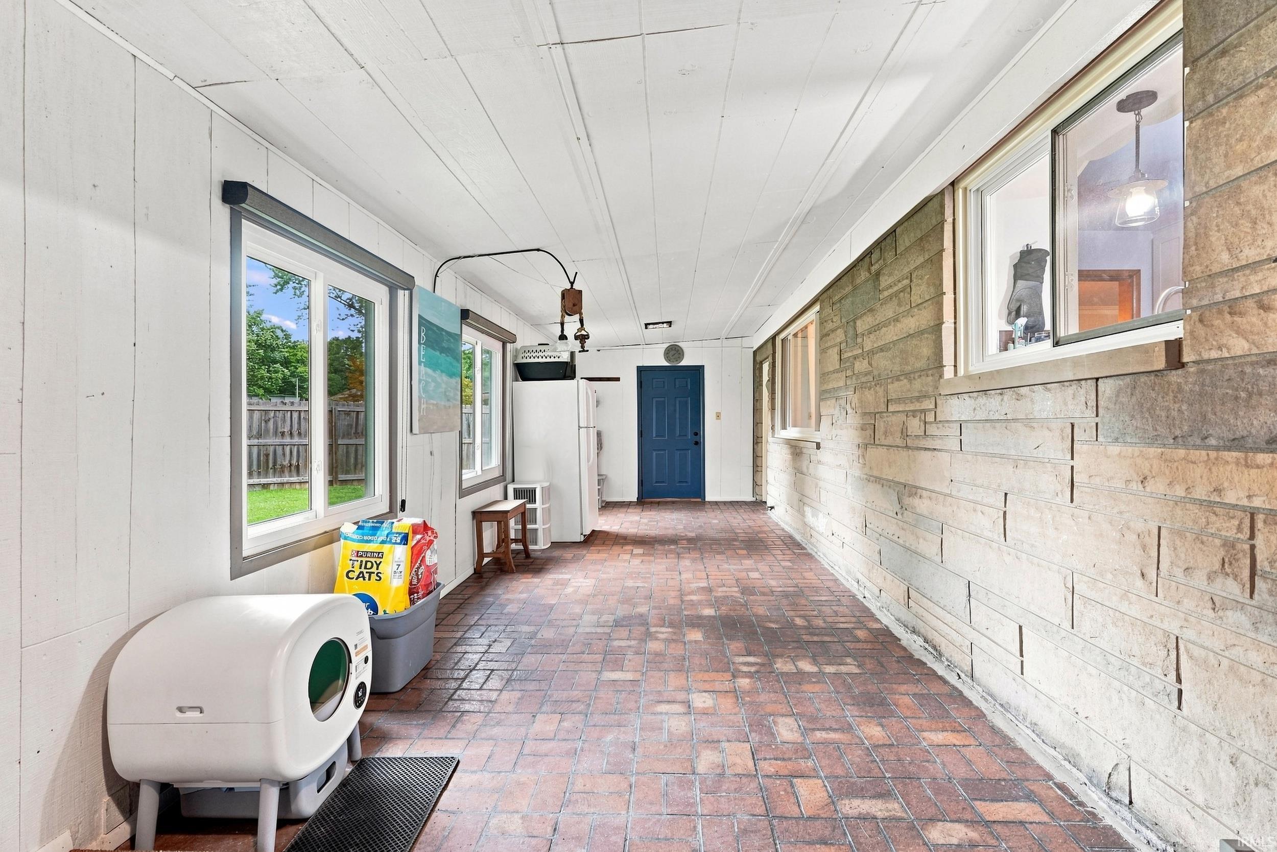 Enclosed porch featuring a brick-patterned floor and white paneled walls