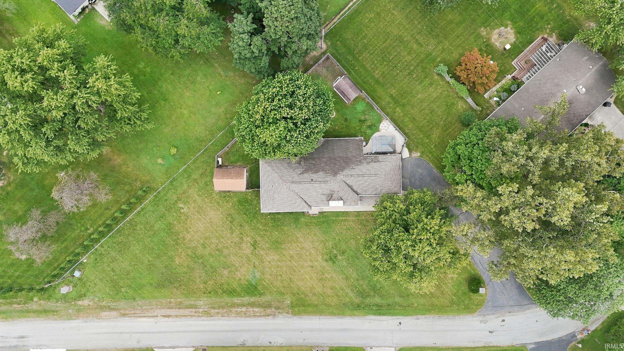 Expansive property with a gabled roofline, mature trees, and an accessory building