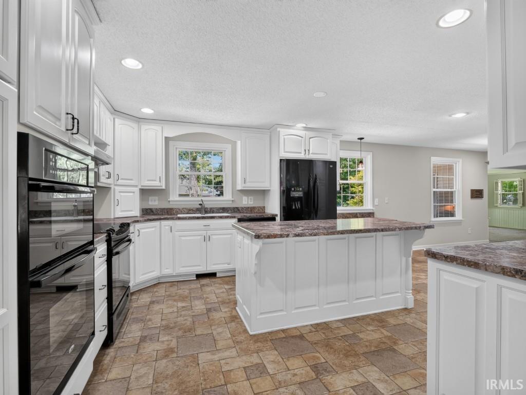 Kitchen featuring white cabinetry, patterned floor tiling, dark-finish appliances, light-toned countertops, and recessed lighting