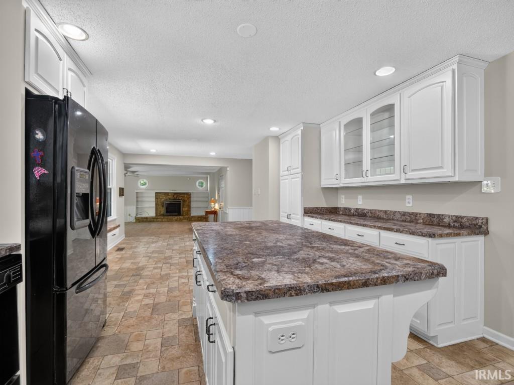 Kitchen featuring a central island, white cabinetry, integrated black refrigerator, and tile flooring