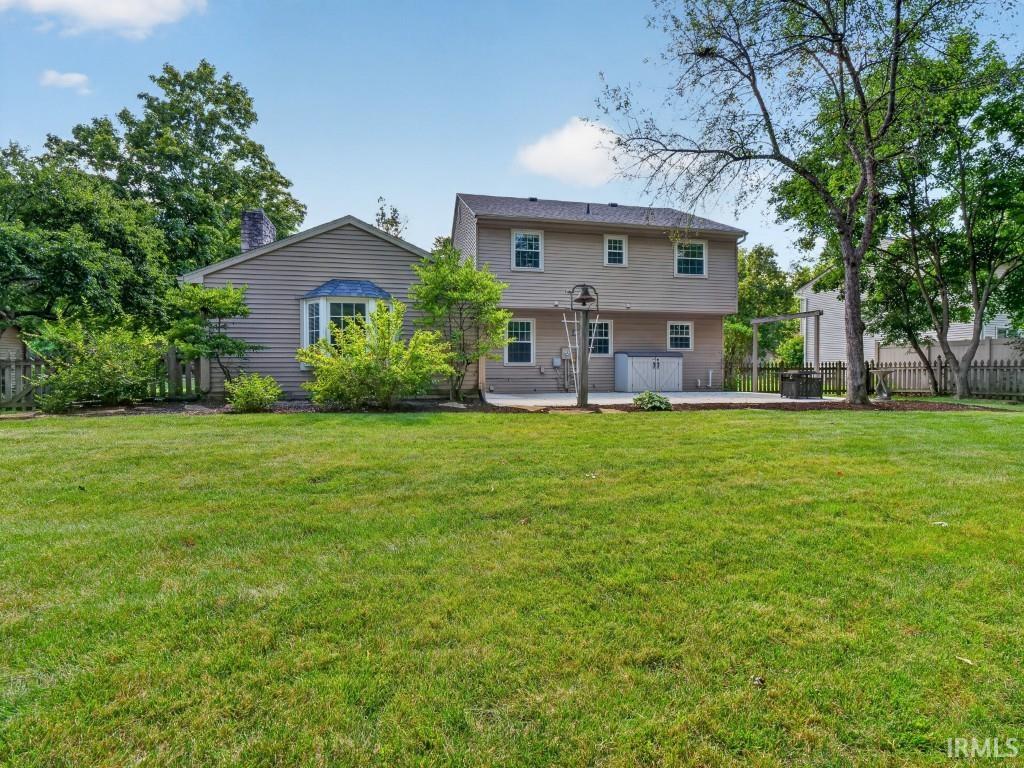 Expansive green lawn, mature trees, and a concrete patio with direct house access
