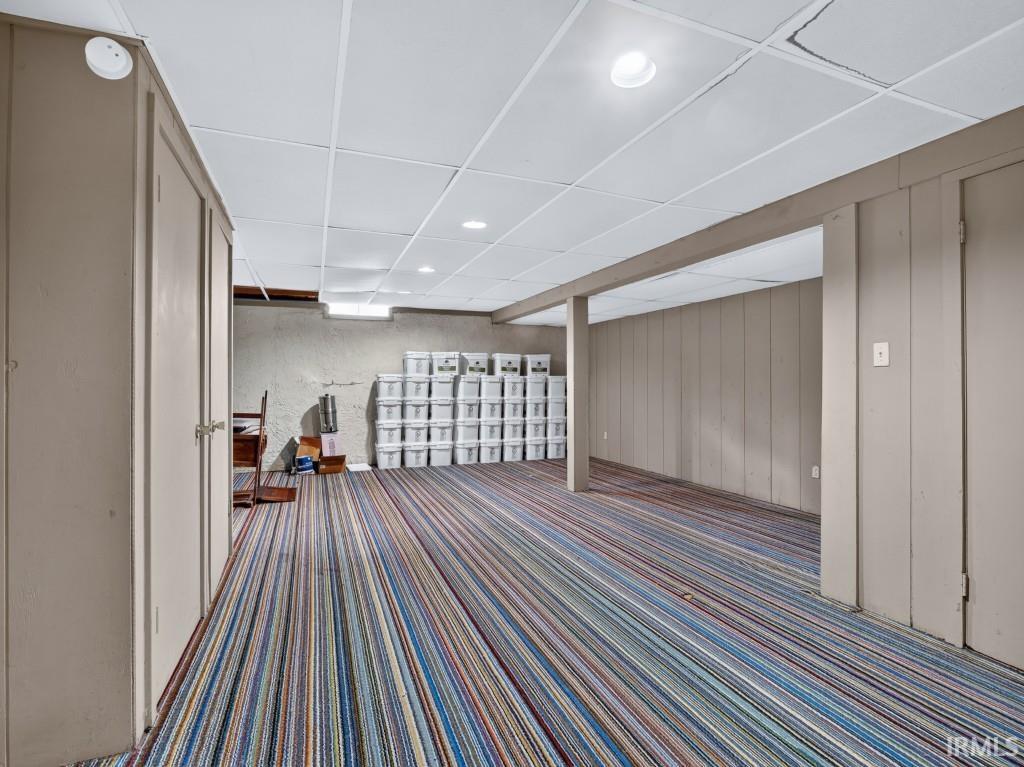 Recessed lighting illuminates the dropped ceiling and striped carpet flooring