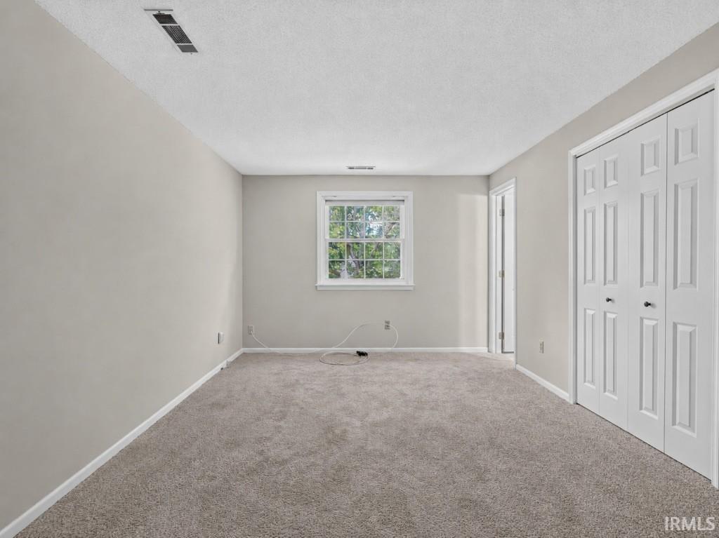 Neutral wall paint, carpeted flooring, a single window, and a white bi-fold closet door