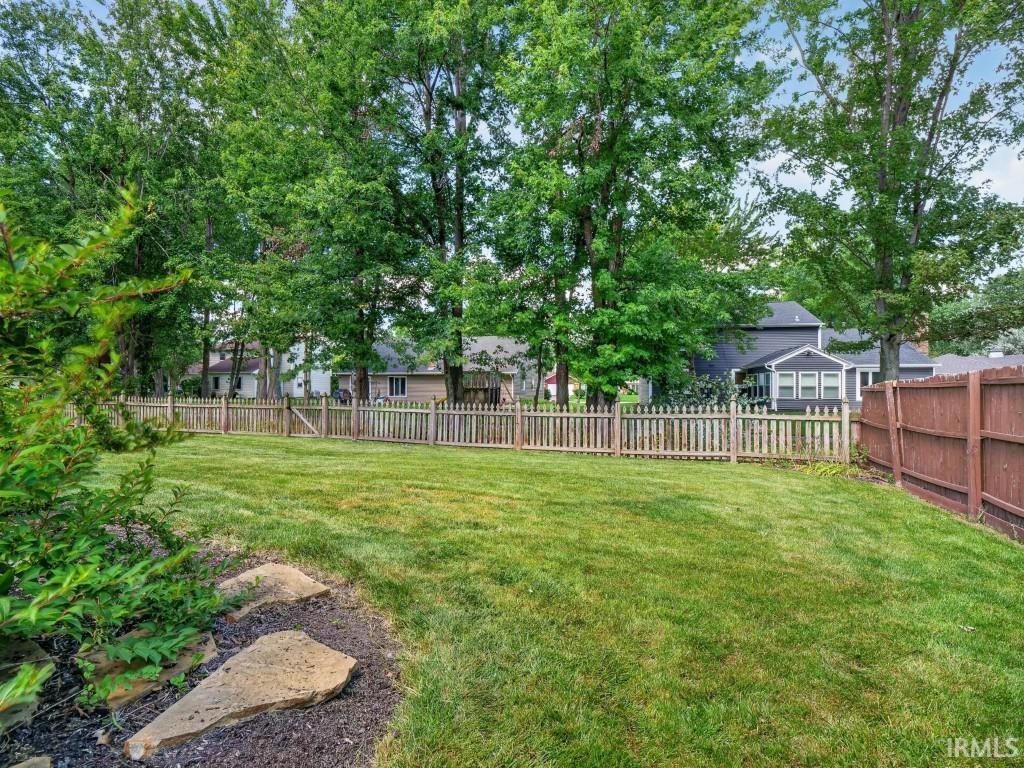 Expansive green lawn with mature trees and a wood picket fence
