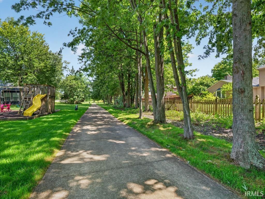 Paved pathway bordered by mature trees and manicured grass