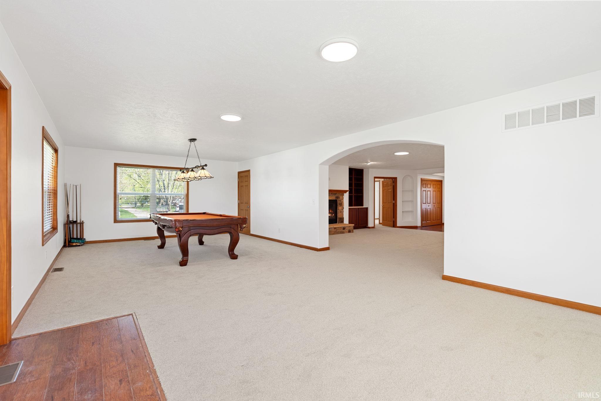 Spacious interior featuring neutral carpeting, white walls, wood-finish trim, and an arched entryway
