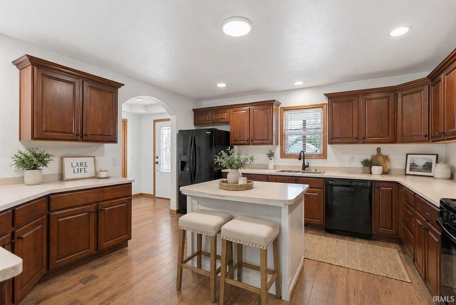 Spacious kitchen featuring dark wood cabinetry, light countertops, wood-finish flooring, a kitchen island, and recessed lighting