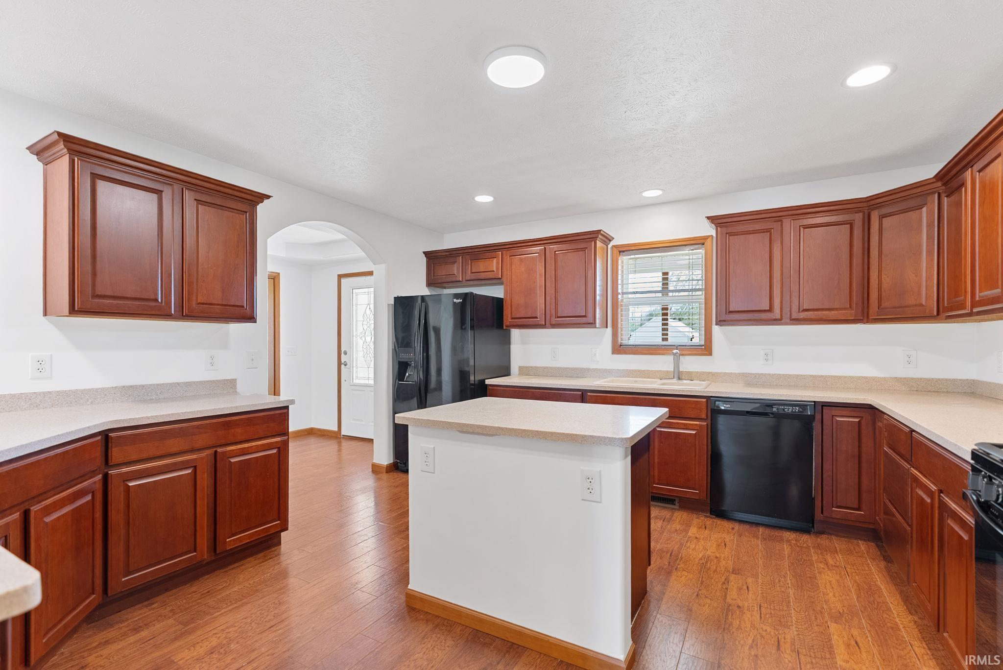 Kitchen with wood-finish flooring, recessed lighting, and a central island