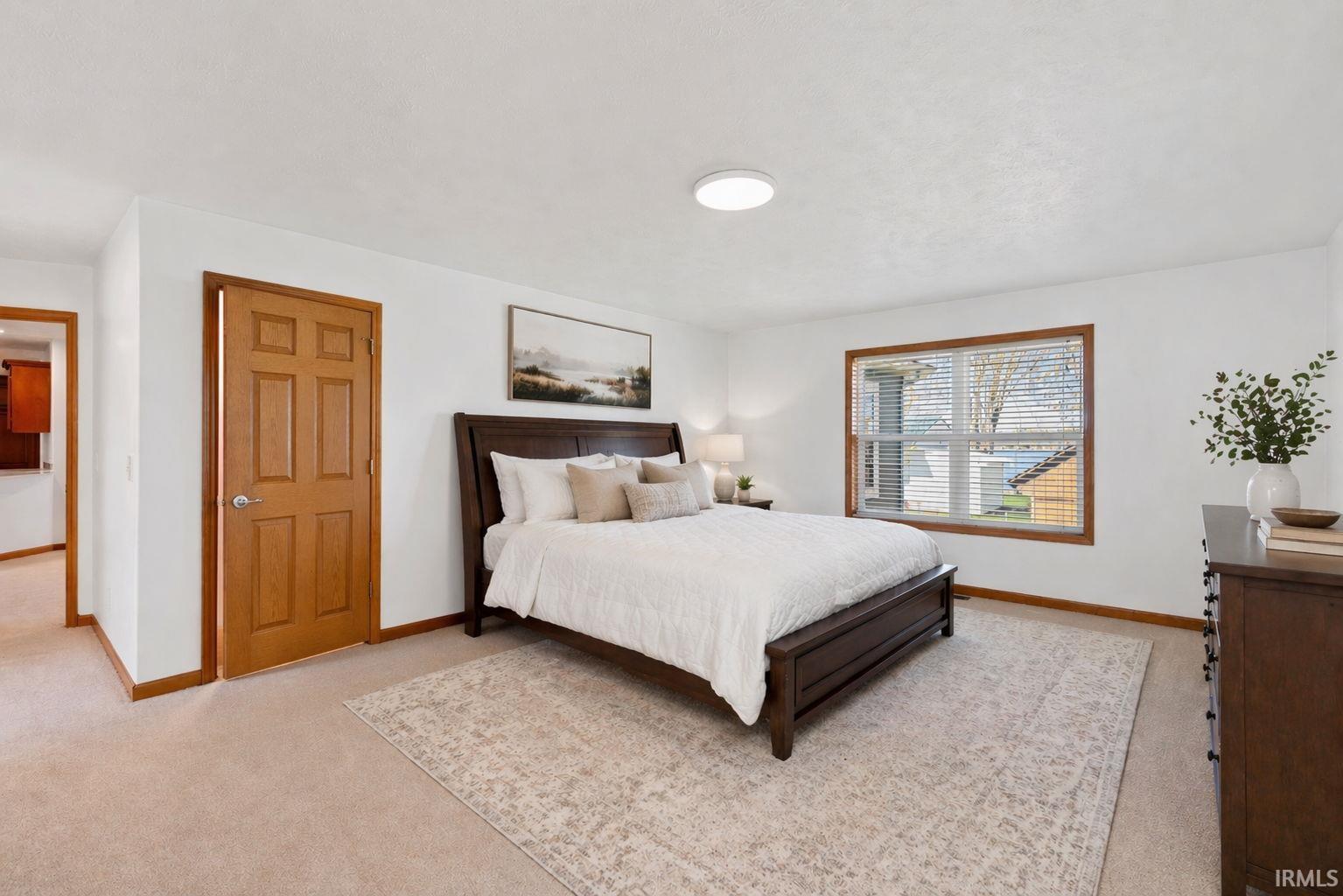 Carpeted room featuring a window with wood trim, a six-panel wood door, and a flush-mount ceiling light fixture
