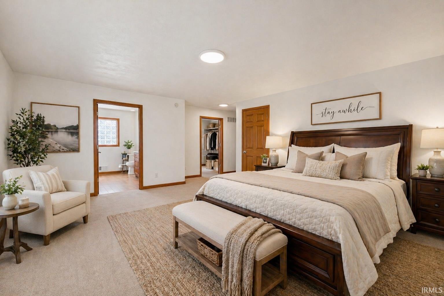 Carpeted bedroom featuring a dark wood bed frame, two recessed ceiling lights, and two open doorways revealing additional interior spaces
