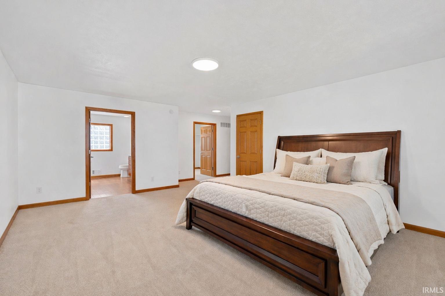 Spacious bedroom featuring light-toned carpeting, white walls, and a recessed ceiling light