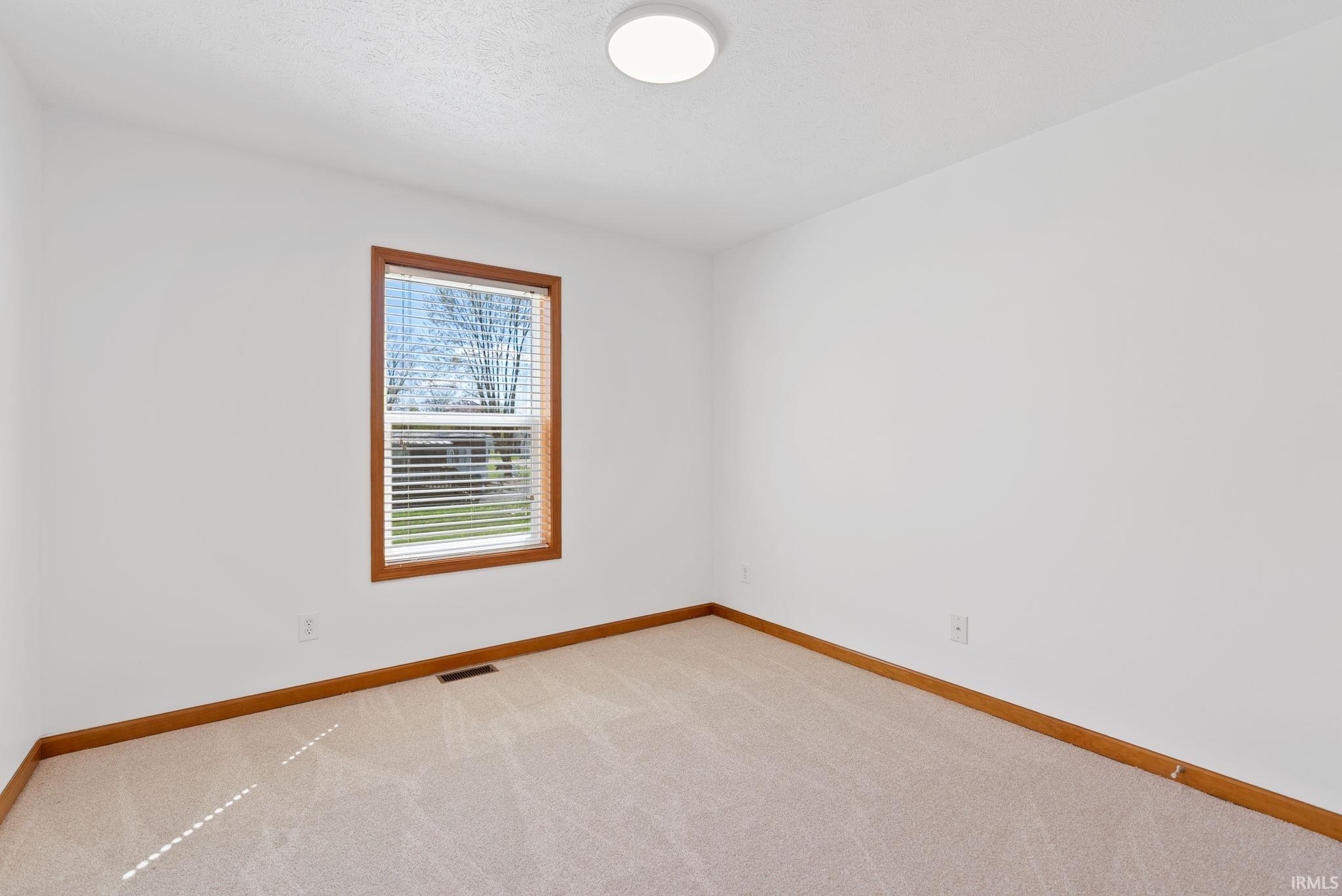 Room featuring neutral carpeting, white walls, and a window with wood trim