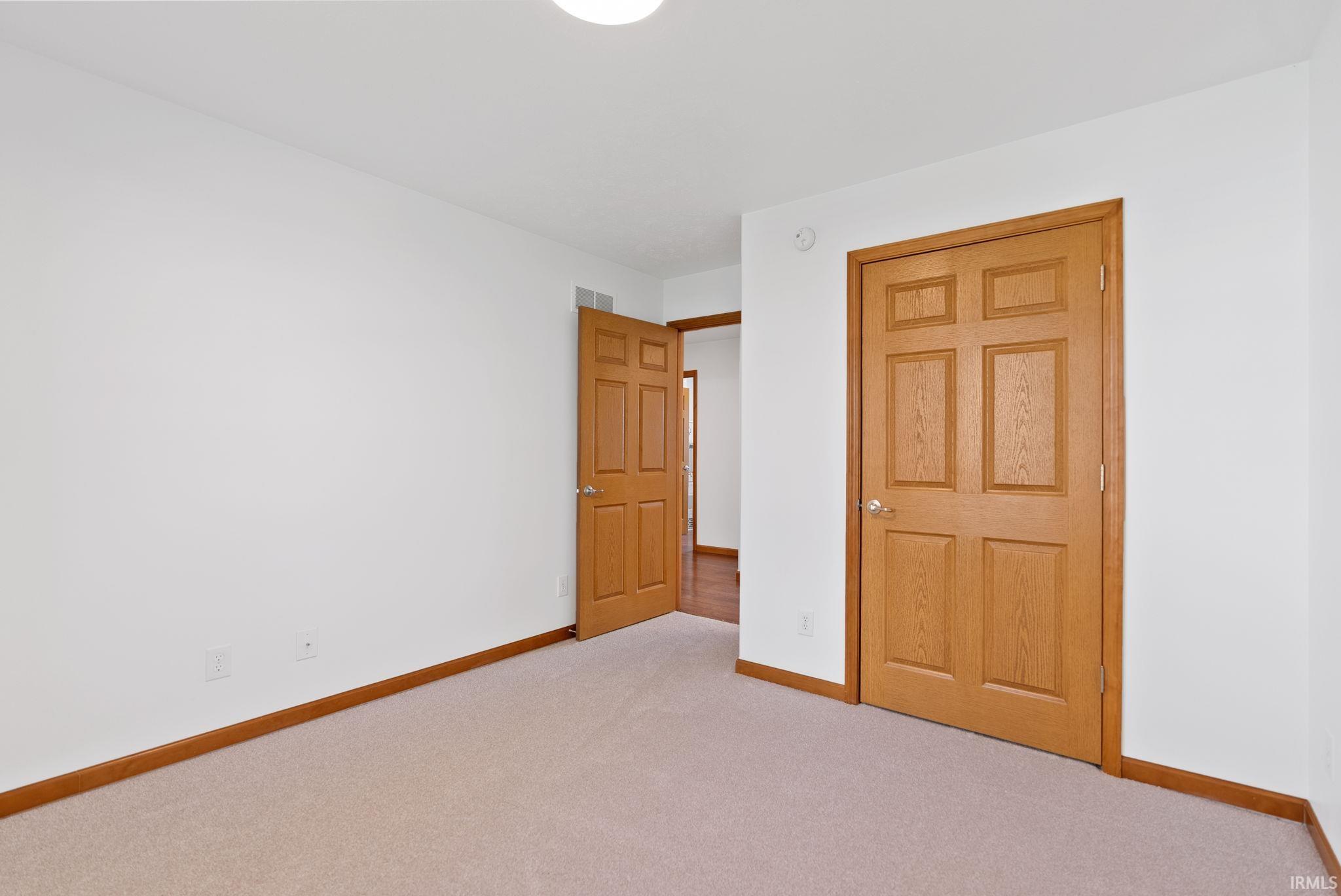 Neutral wall paint and carpeting with natural wood trim and doors