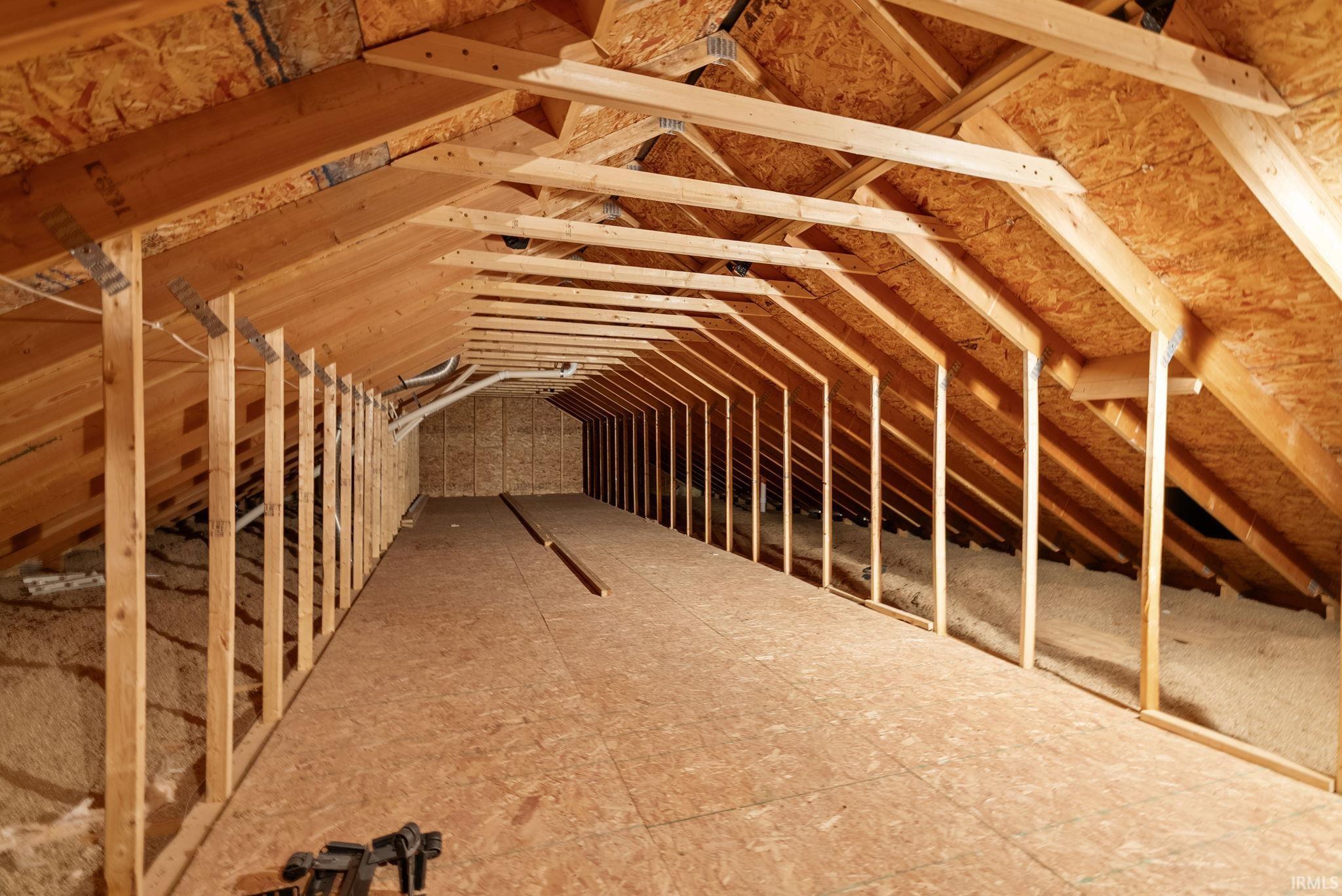 Spacious attic featuring exposed wood framing, oriented strand board flooring, and visible insulation