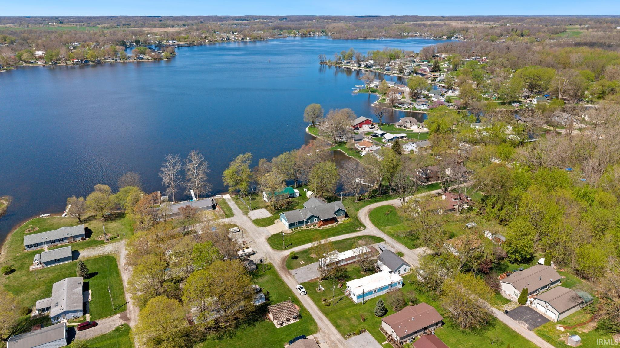 Expansive waterfront property featuring a large lake, surrounding lush green trees, and multiple residential structures
