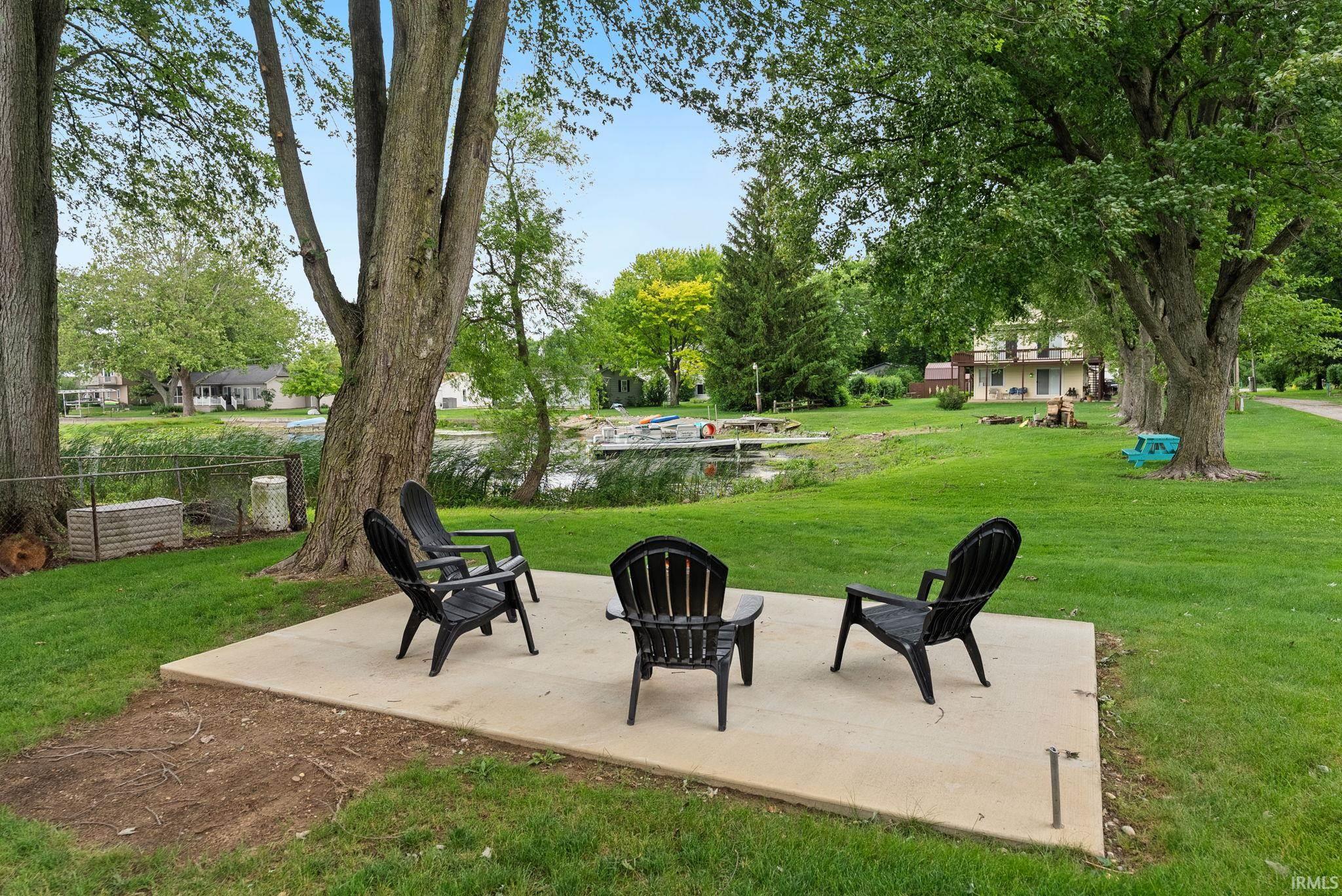 Expansive green lawn with mature trees and a concrete patio