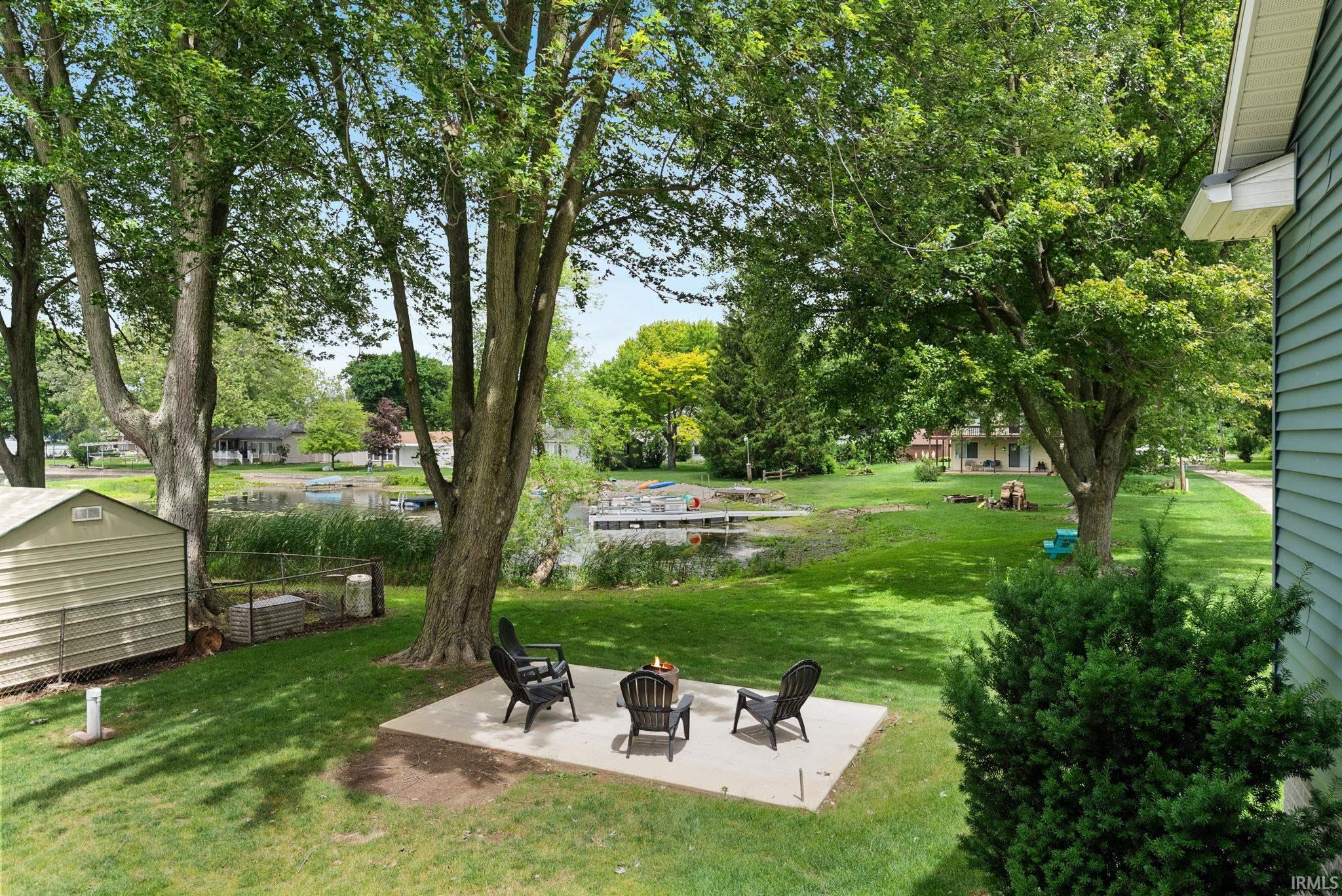 Expansive green lawn with mature trees and a concrete patio
