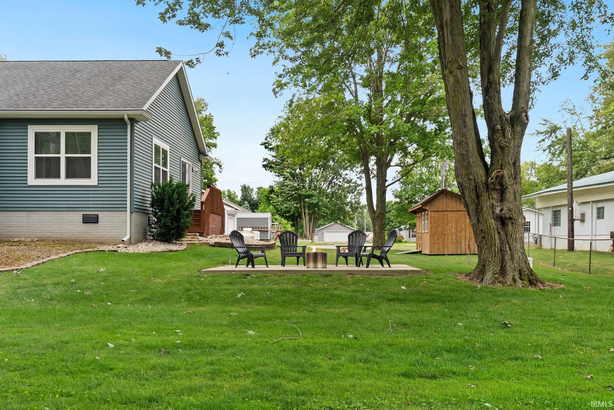 Expansive lawn with a concrete patio featuring a built-in fire pit