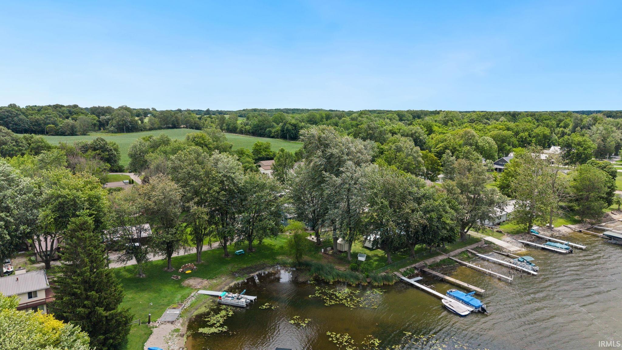 Lakeside property featuring multiple boat docks, mature trees, and a grassy shoreline