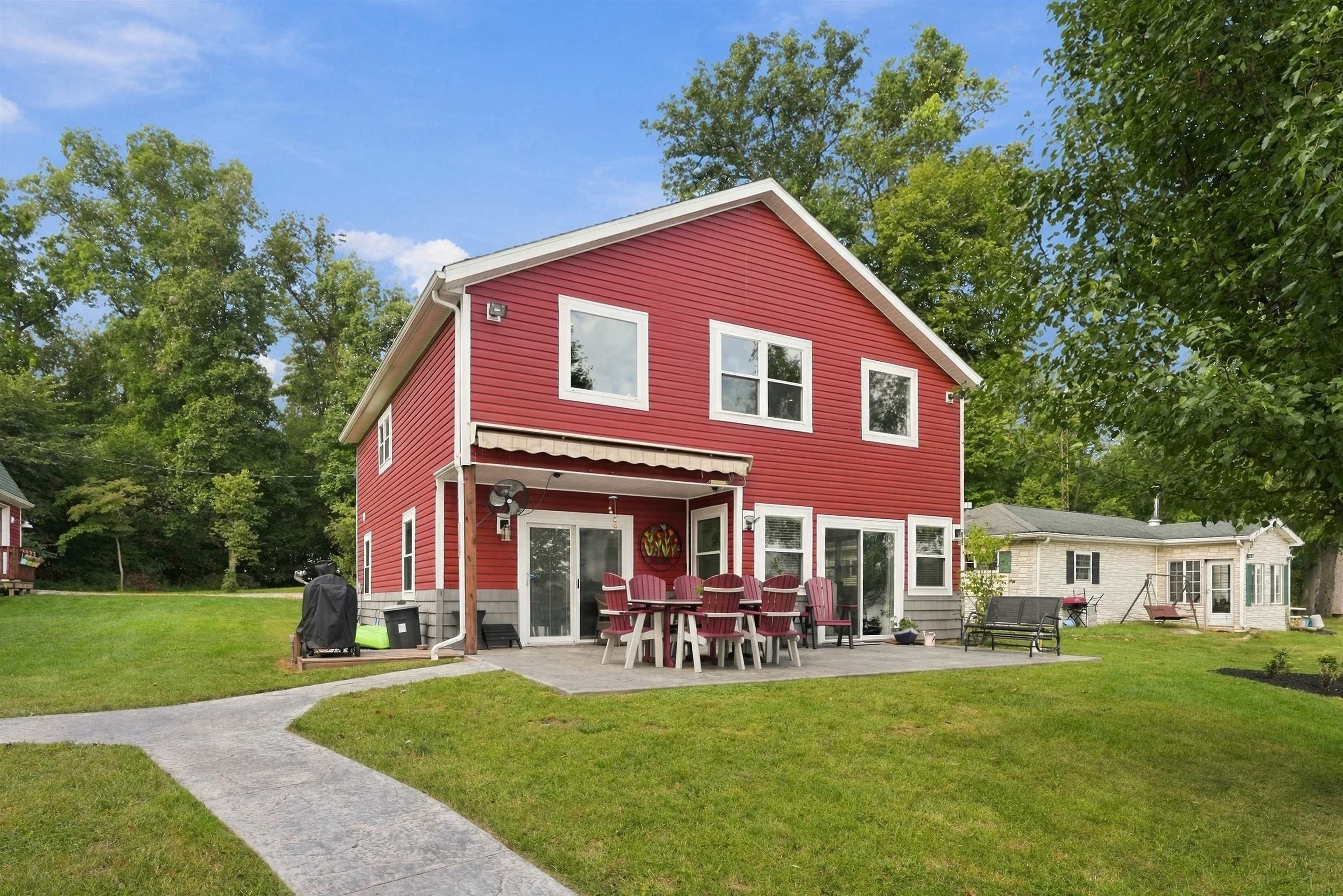 Red siding exterior with white trim windows and a concrete patio