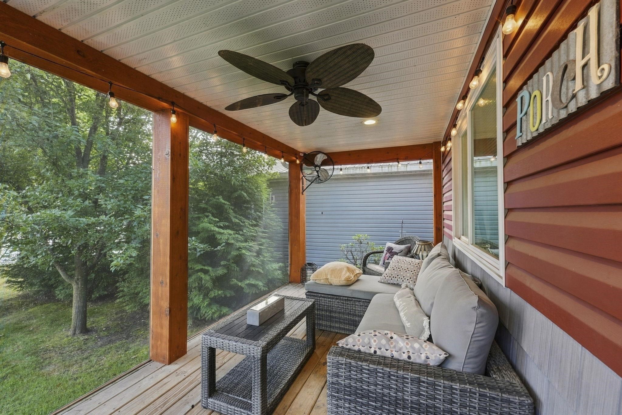 Screened porch featuring wood-finish flooring, wood support beams, string lighting, and a ceiling fan