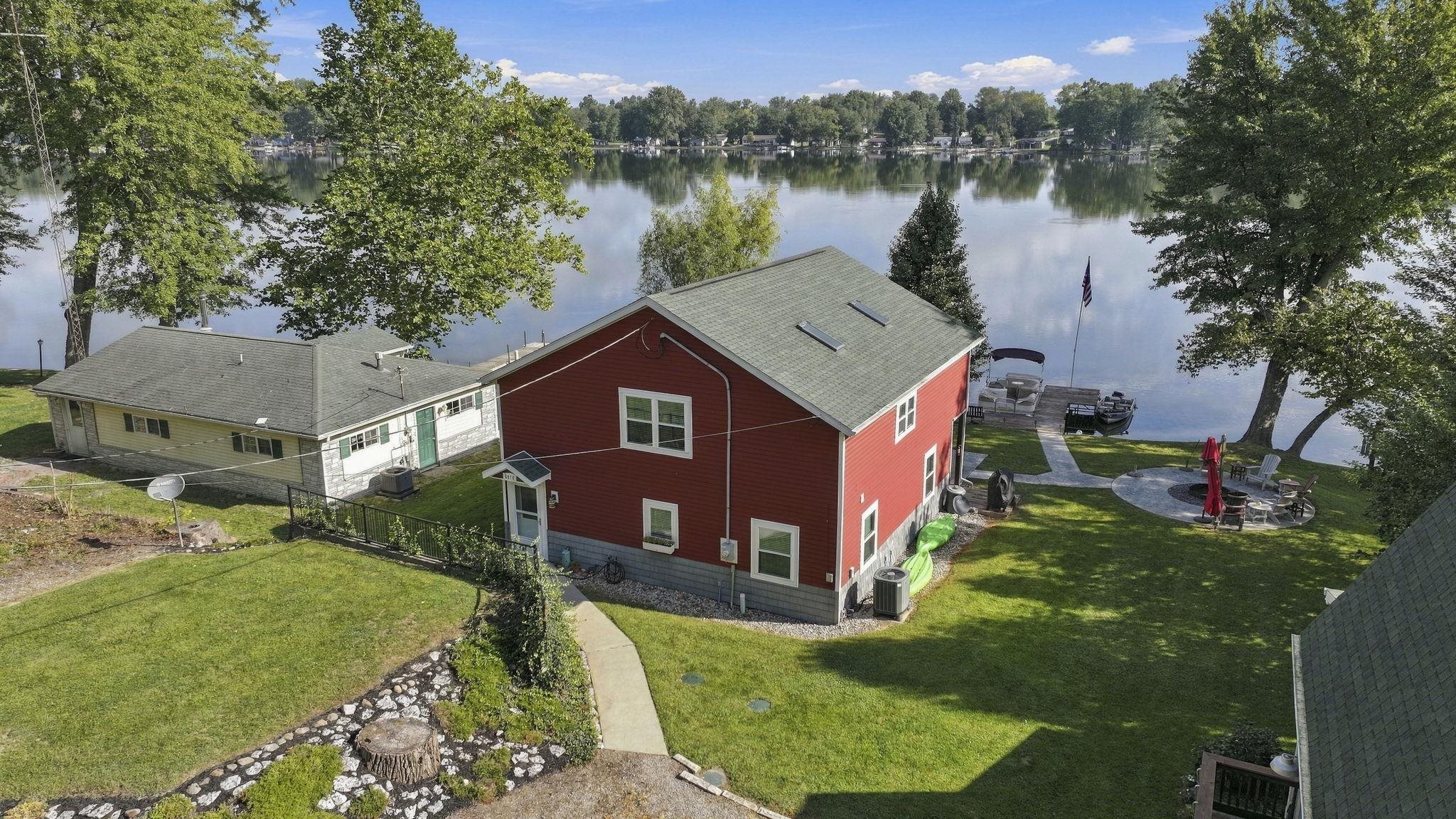 Red-sided property with a pitched roof, featuring a private dock extending into the water