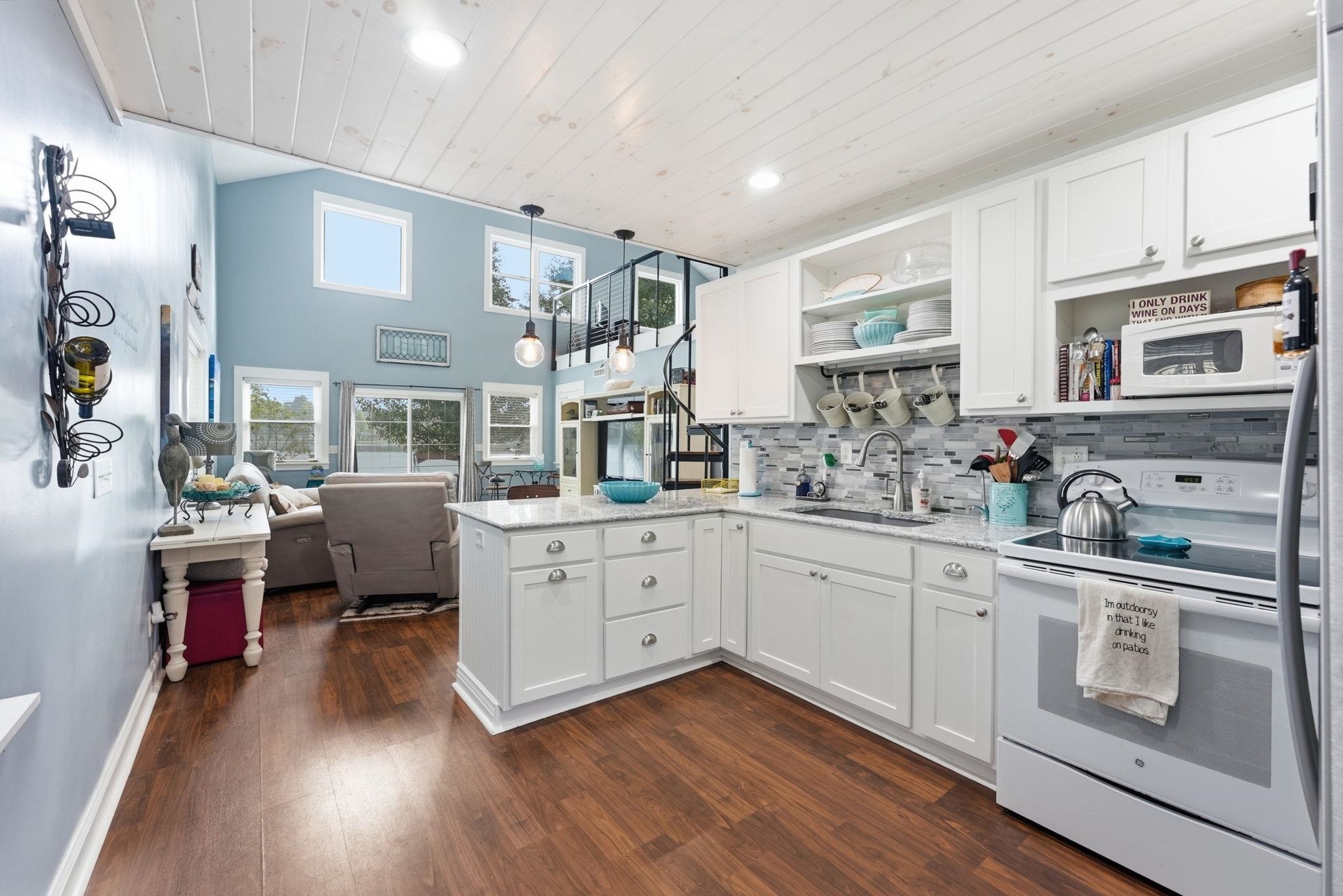 Kitchen featuring white cabinetry, light-colored countertops, a tile backsplash, and wood-finish flooring