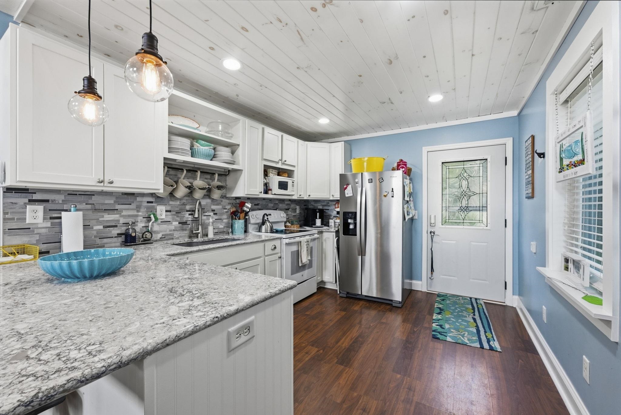 Kitchen featuring white cabinetry, a mosaic tile backsplash, stone countertops, wood-finish flooring, and a decorative glass panel door