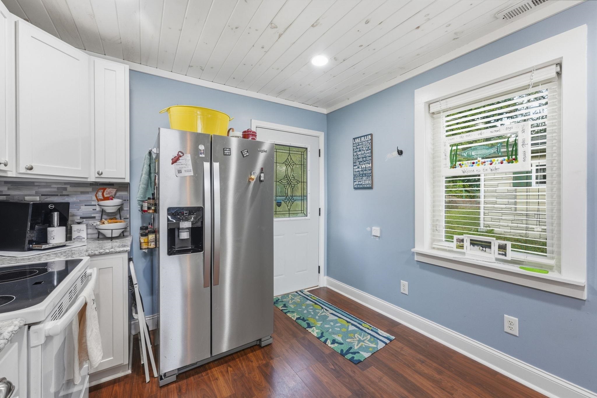 White shaker cabinetry, wood-finish flooring, recessed lighting, and a window with white trim