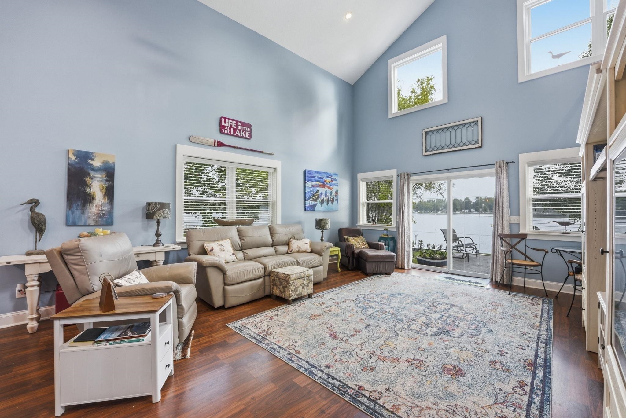 Vaulted ceiling living area featuring wood-finish flooring and a sliding glass door opening to an outdoor deck