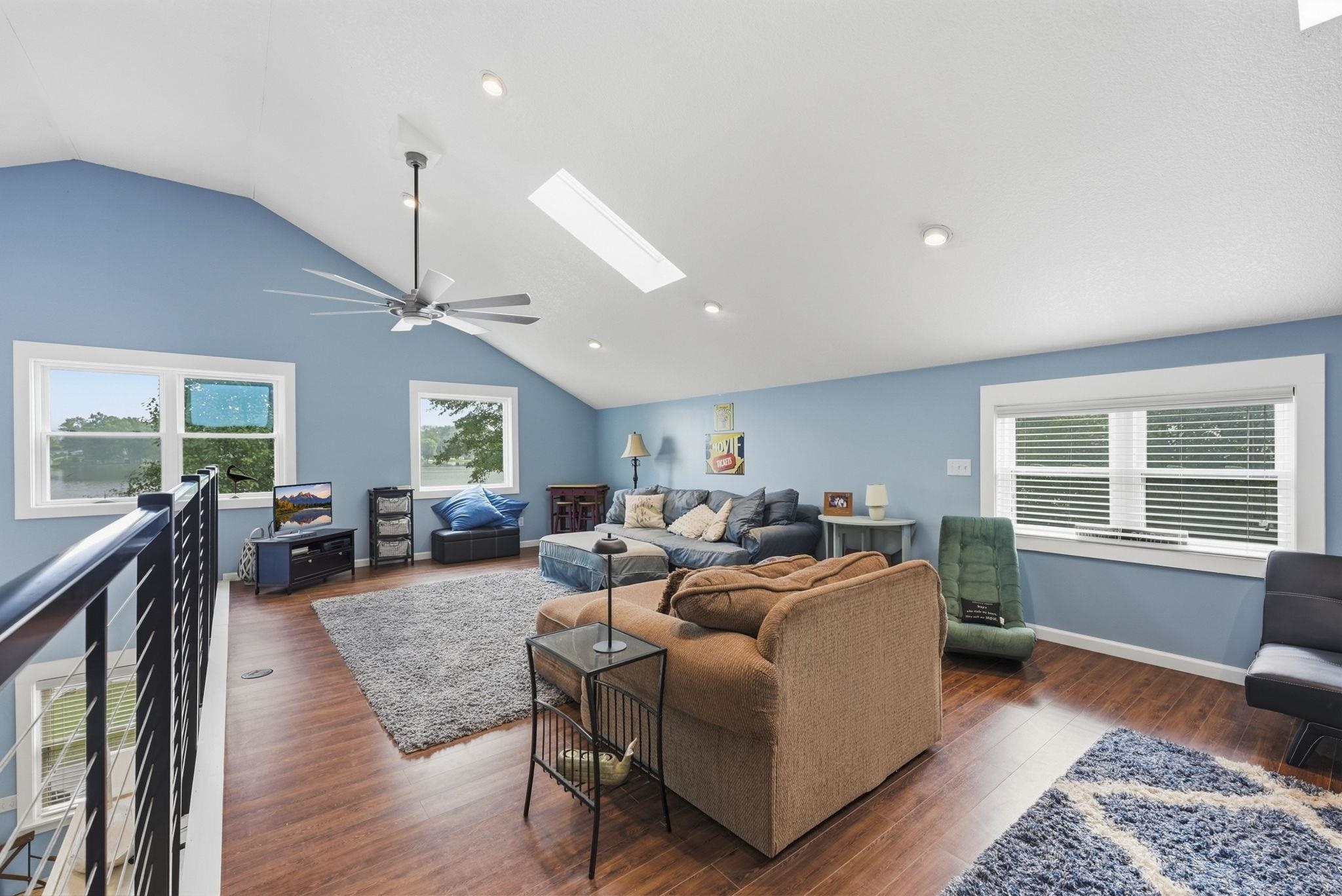 Vaulted ceilings with recessed lighting, wood-finish flooring, and multiple windows