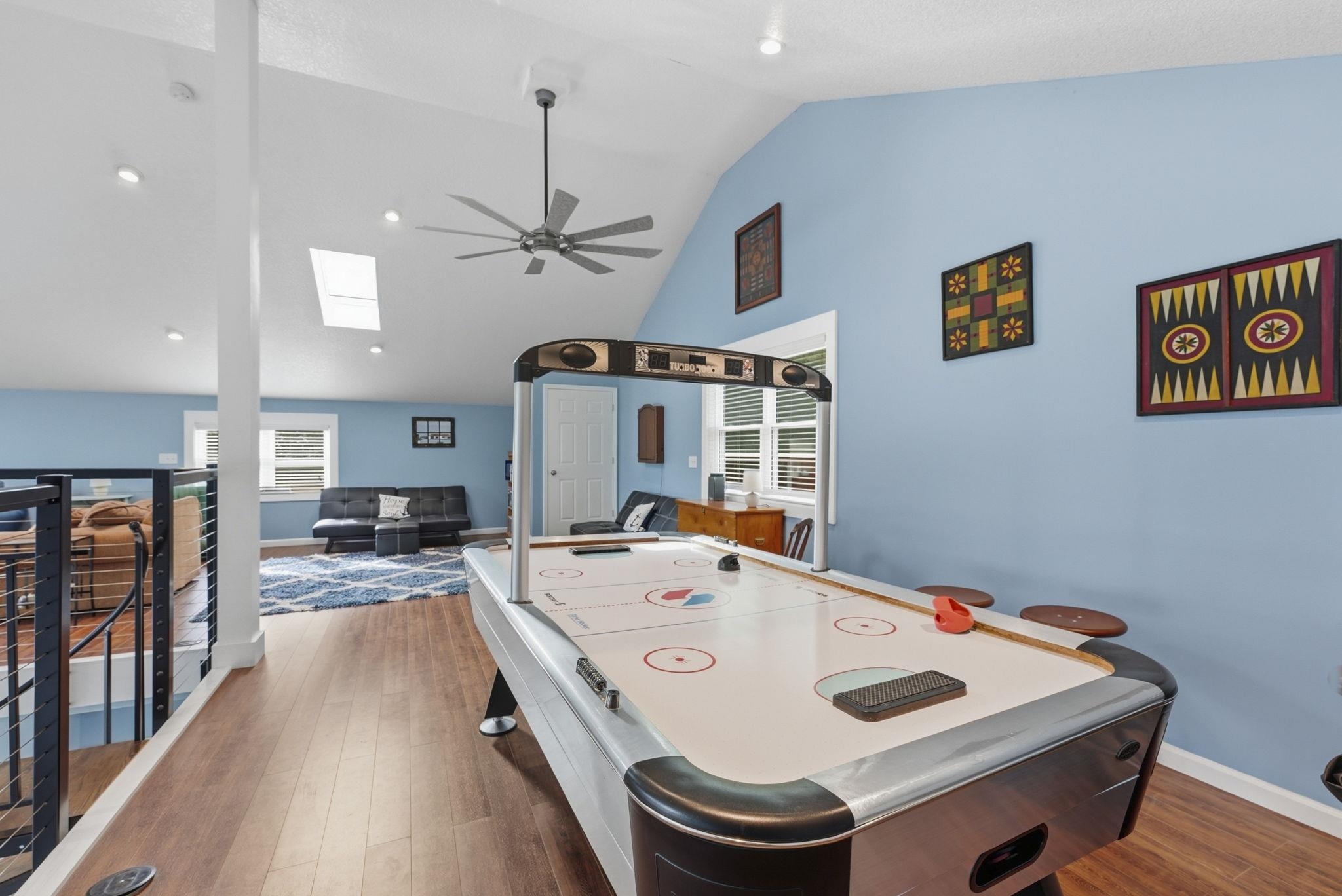 Vaulted ceilings with skylights and recessed lighting, wood-finish flooring, and a contemporary ceiling fan