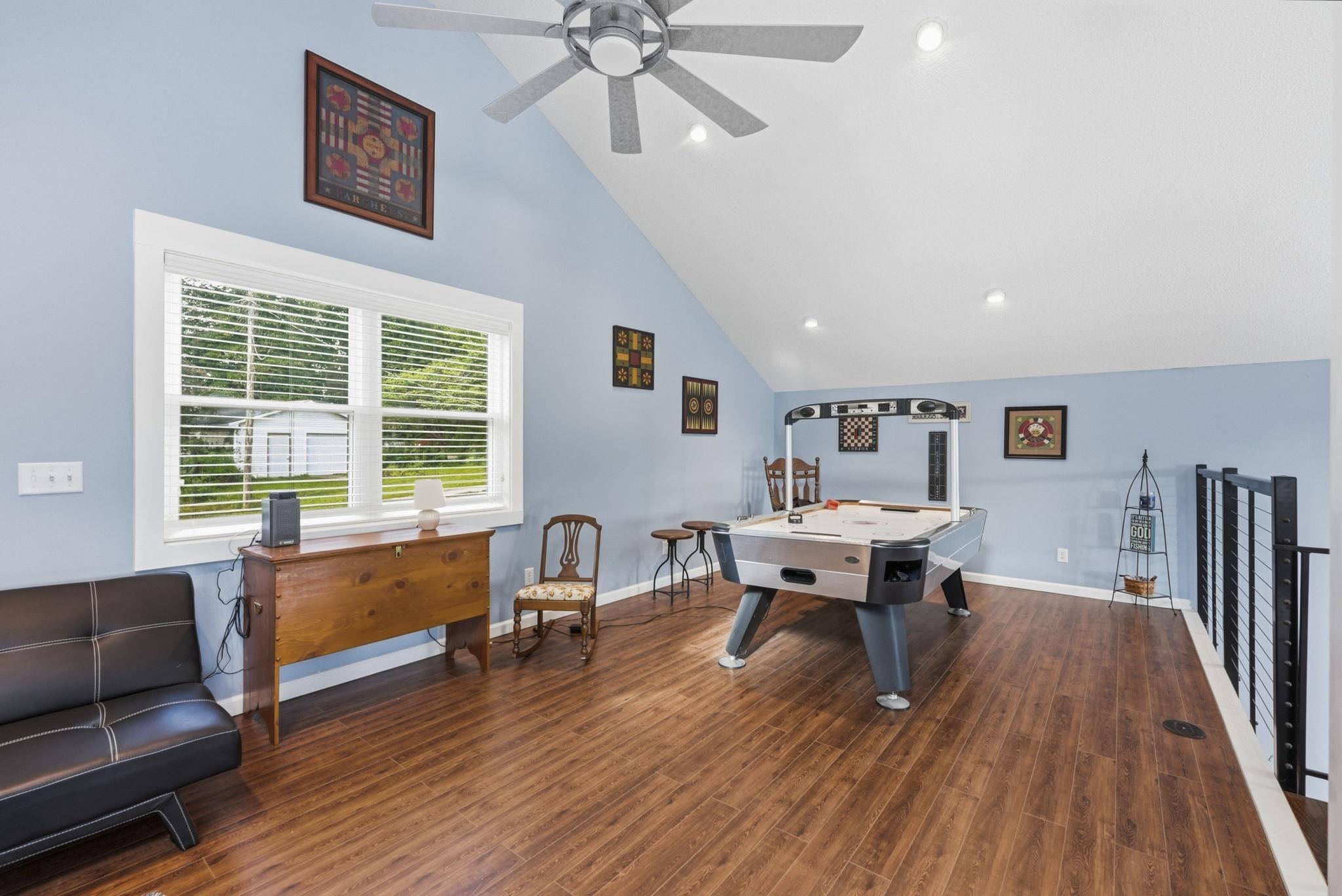 Vaulted ceilings with recessed lighting, wood-finish flooring, white-framed window with louvered blinds, and modern railing