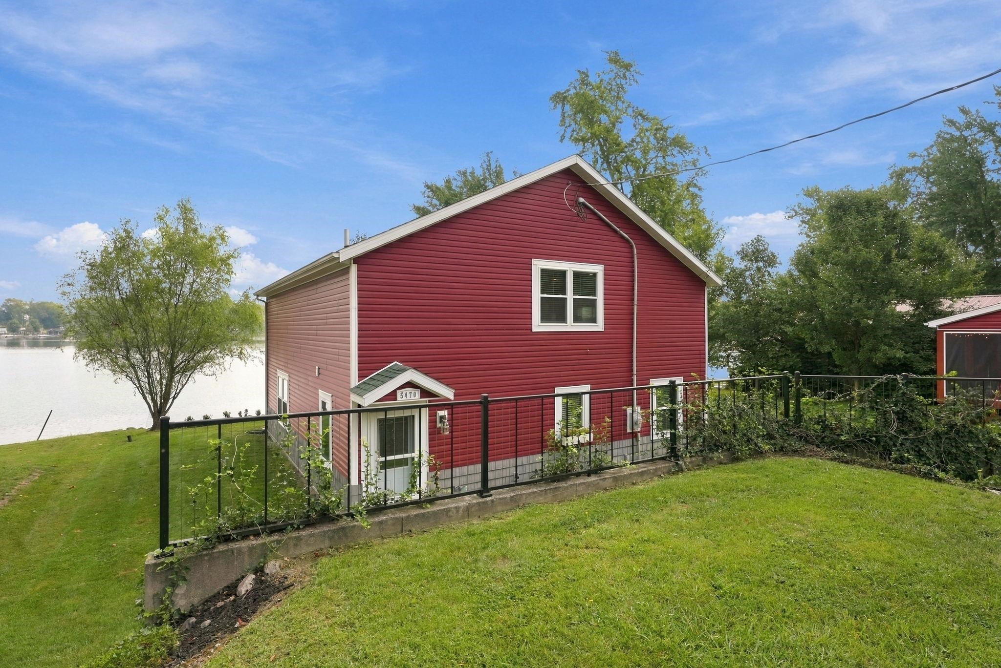 Red siding exterior with white trim windows and a black metal fence