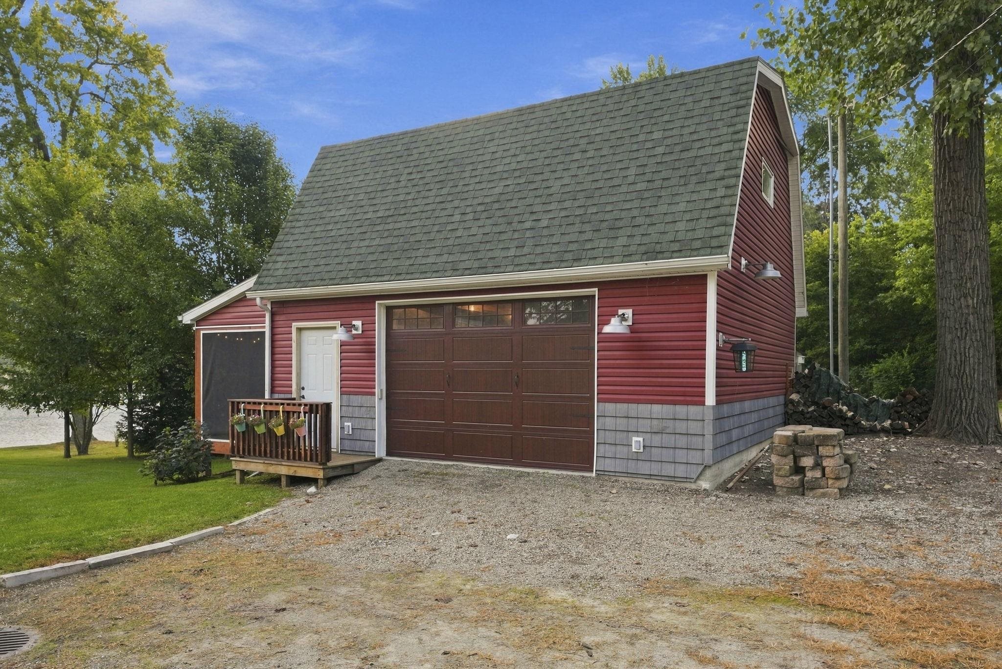 Red vinyl siding with gray shingle accents, a brown garage door, and a green shingle roof