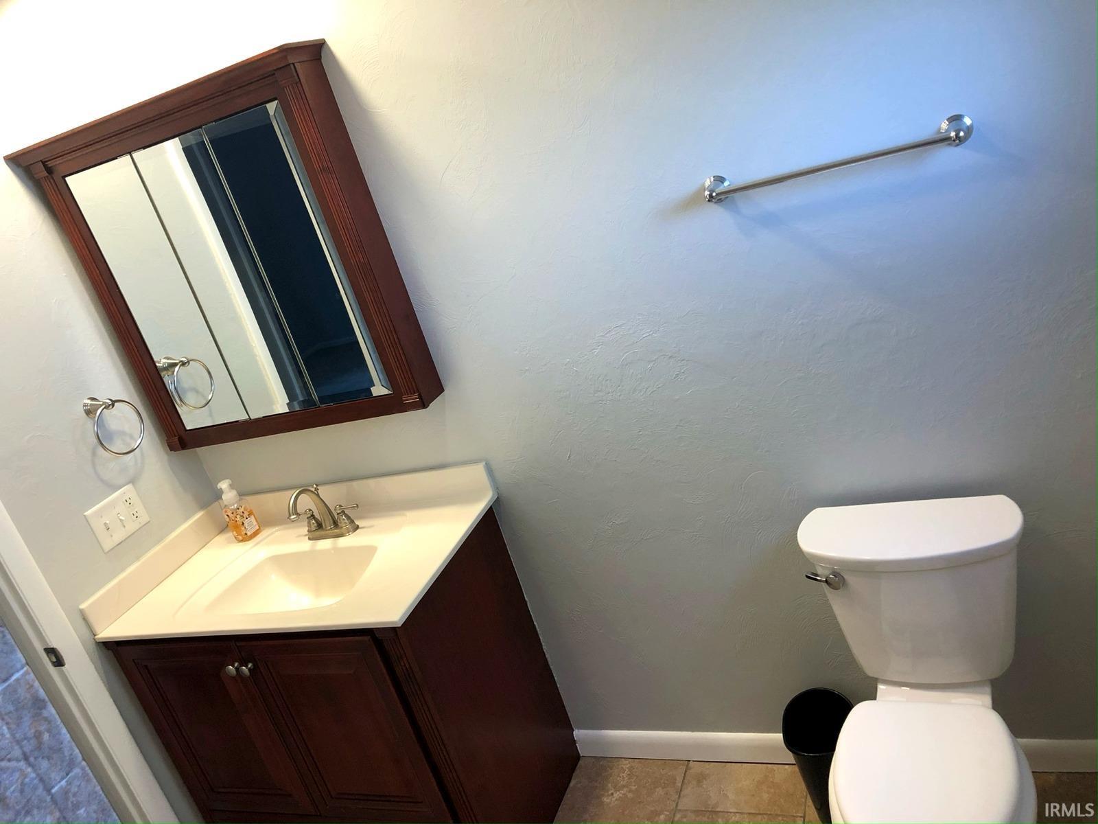 Vanity with wood-finish cabinetry, integrated sink, and white countertop