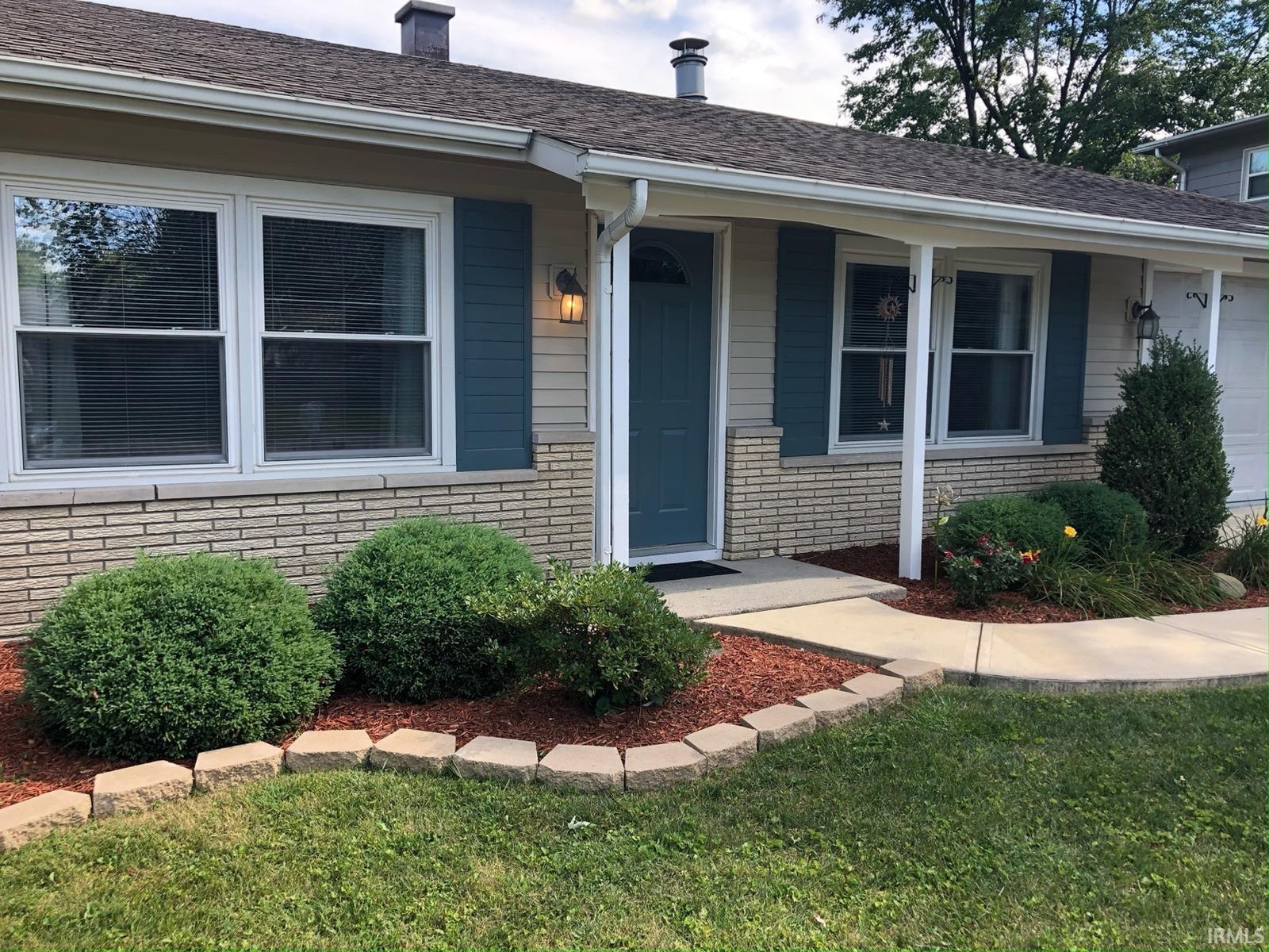 Exterior featuring a composite shingle roof, light brick veneer, horizontal siding, and a concrete pathway