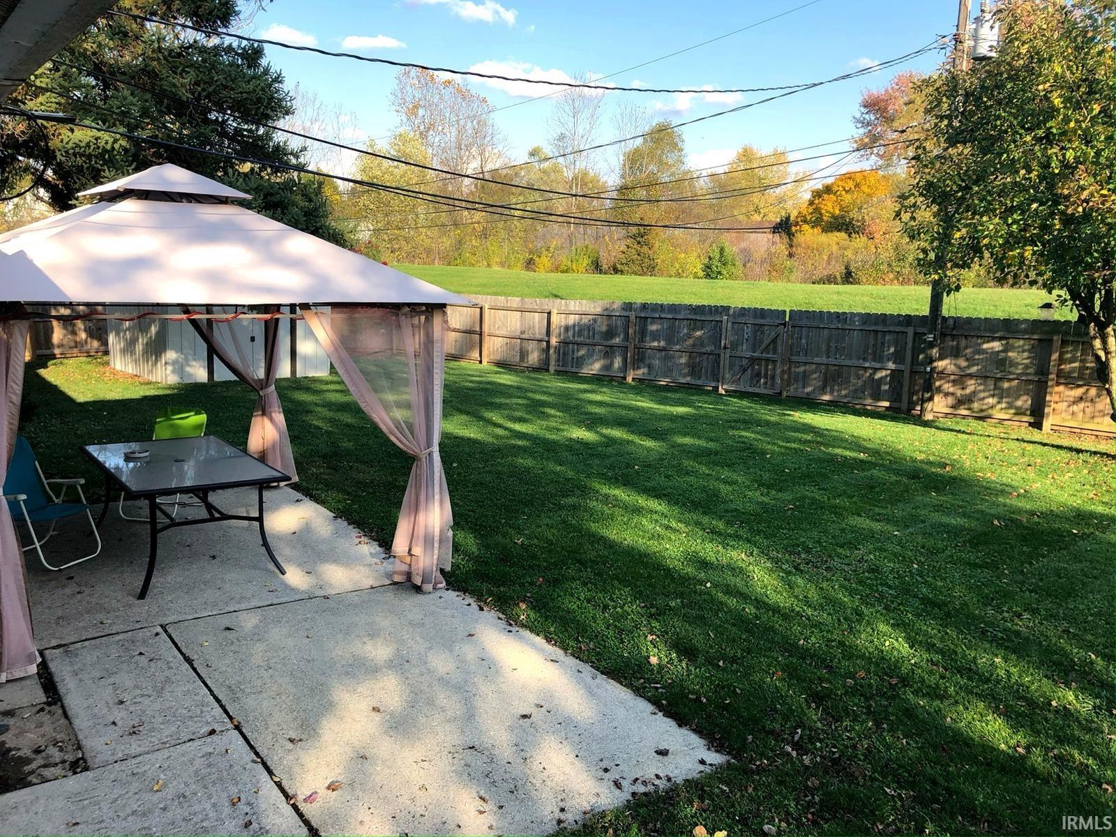 Expansive backyard featuring a manicured lawn, wood fencing, and a concrete patio