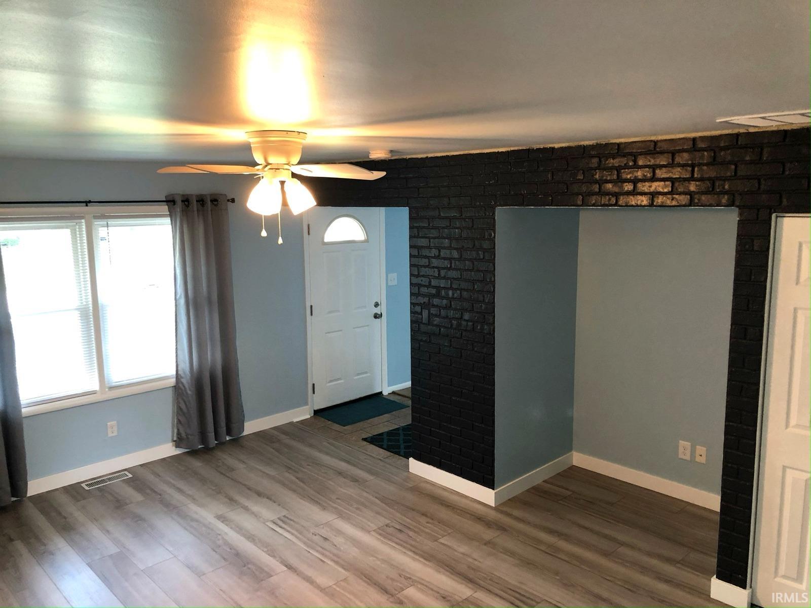 Wood-finish flooring, white trim, and a white paneled entry door with an arched window