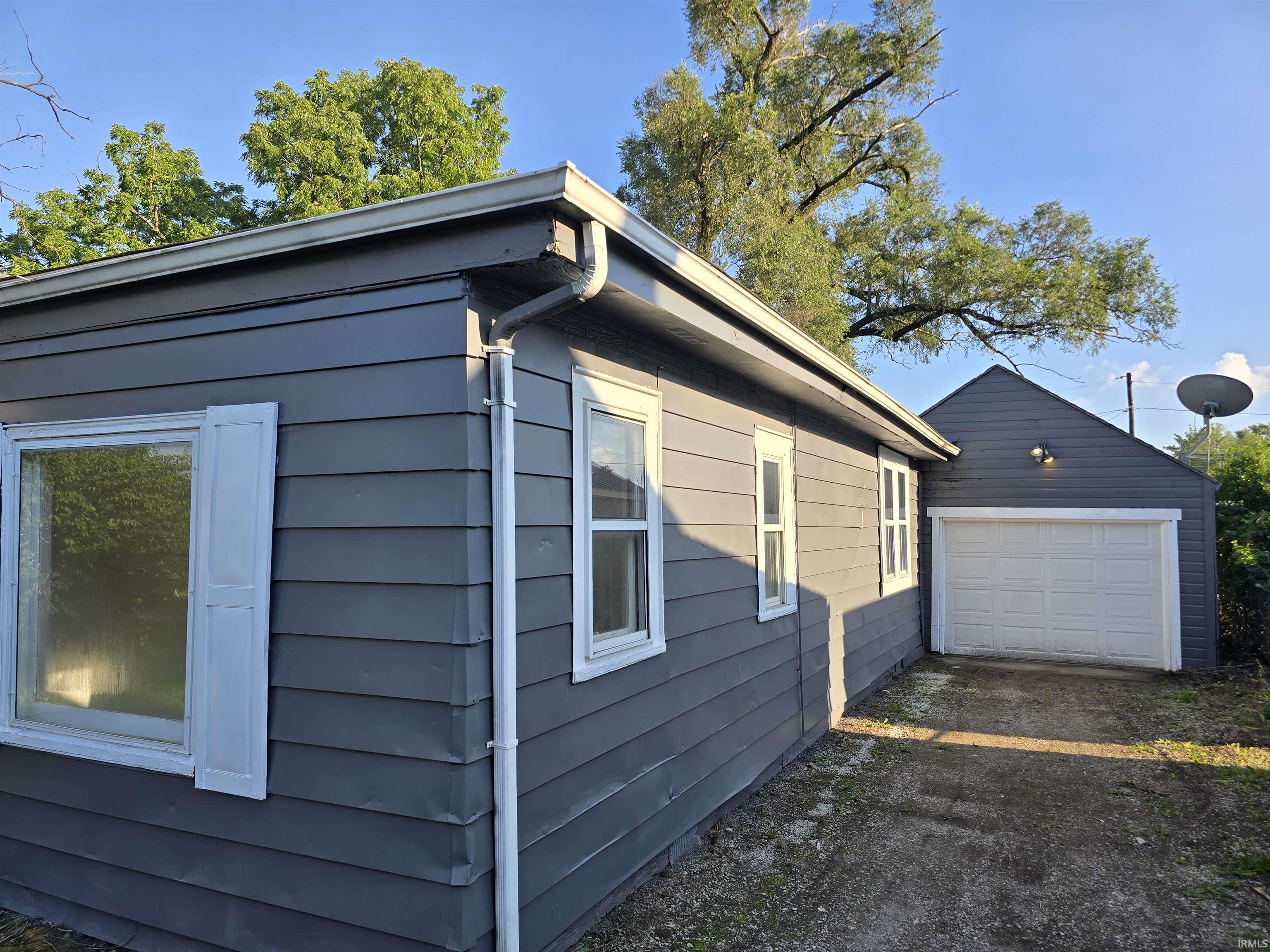Exterior featuring horizontal siding, white trim, and a detached garage with a white panel door
