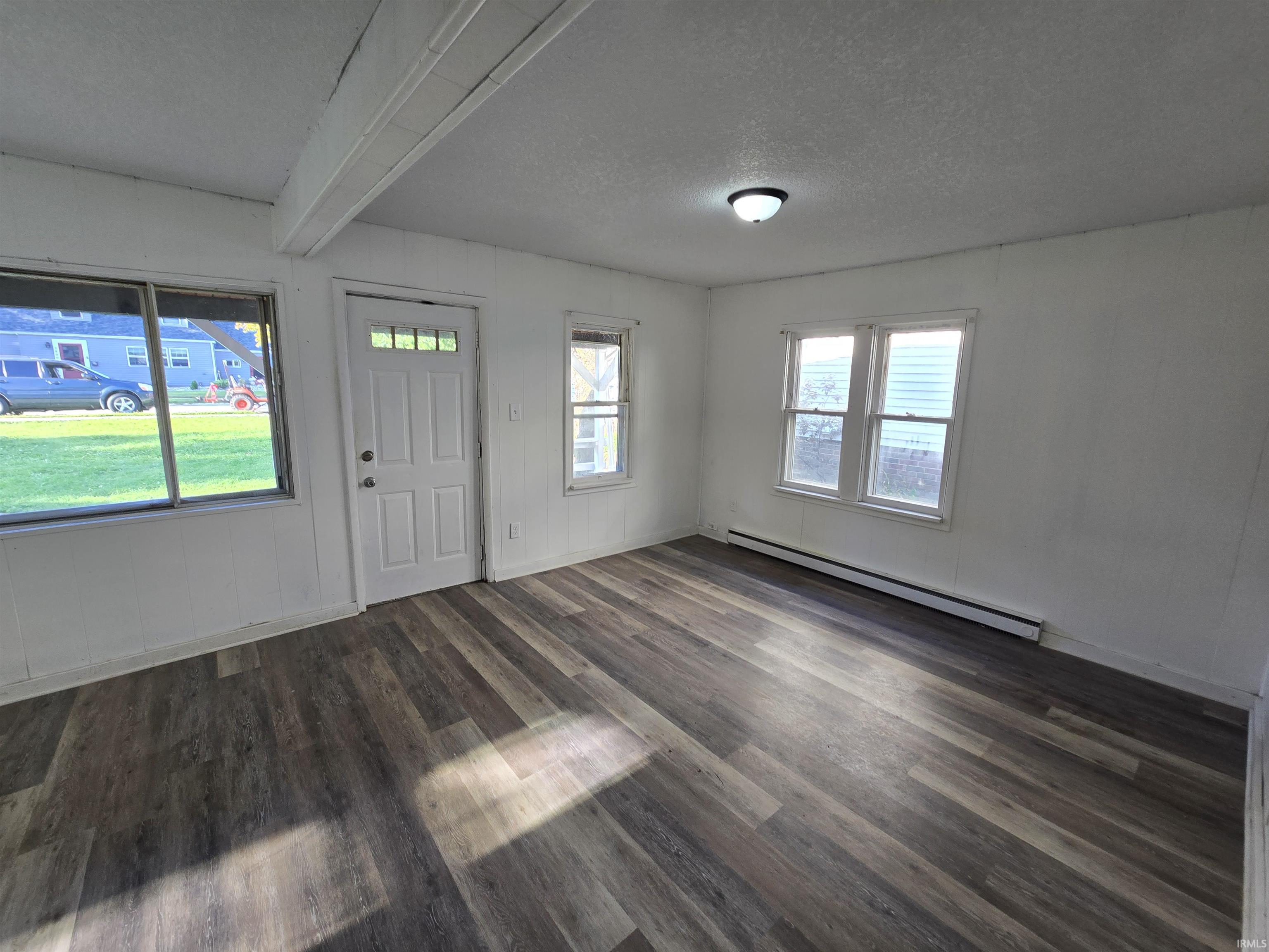 Wood-finish flooring throughout, multiple windows, and a white entry door with glass inserts