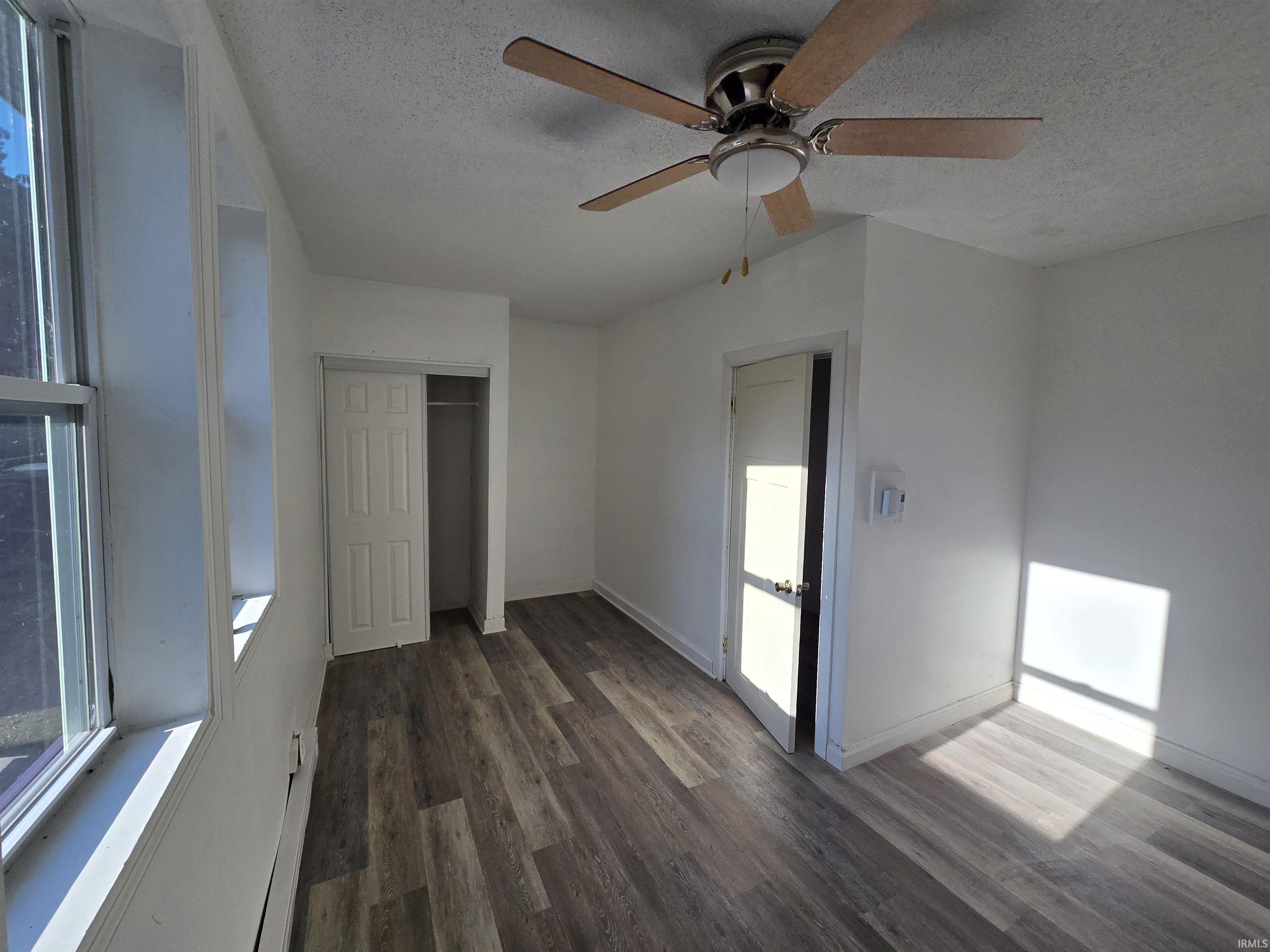 Wood-finish flooring, ceiling fan with integrated lighting, white interior doors, and a built-in closet with bi-fold doors