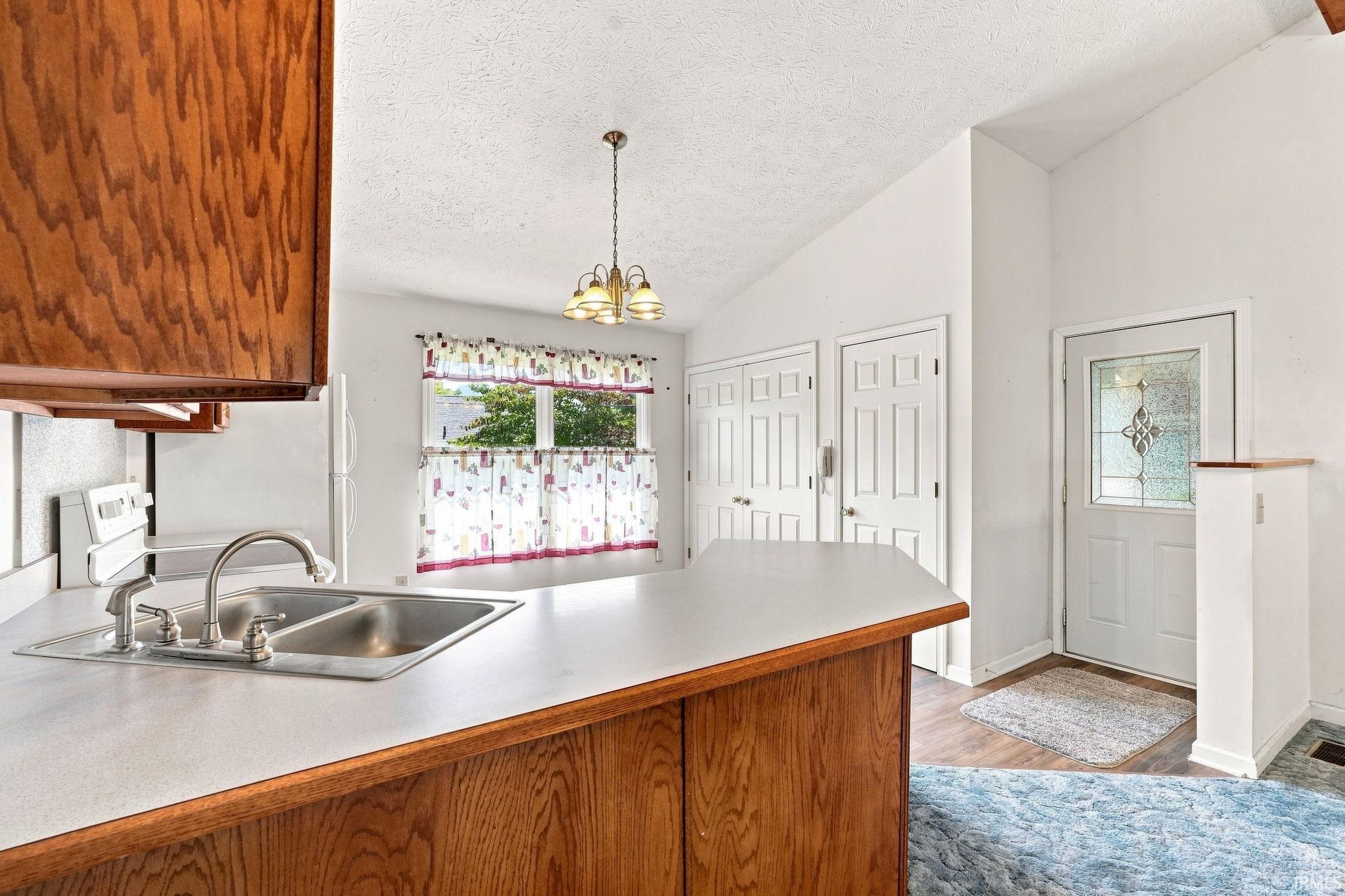 Kitchen with wood-finish cabinetry, stainless steel double basin sink, and a white countertop