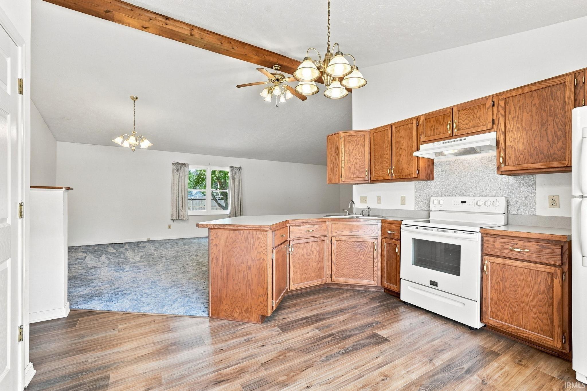Kitchen area with wood-finish flooring, a breakfast bar, wood cabinetry, and white appliances