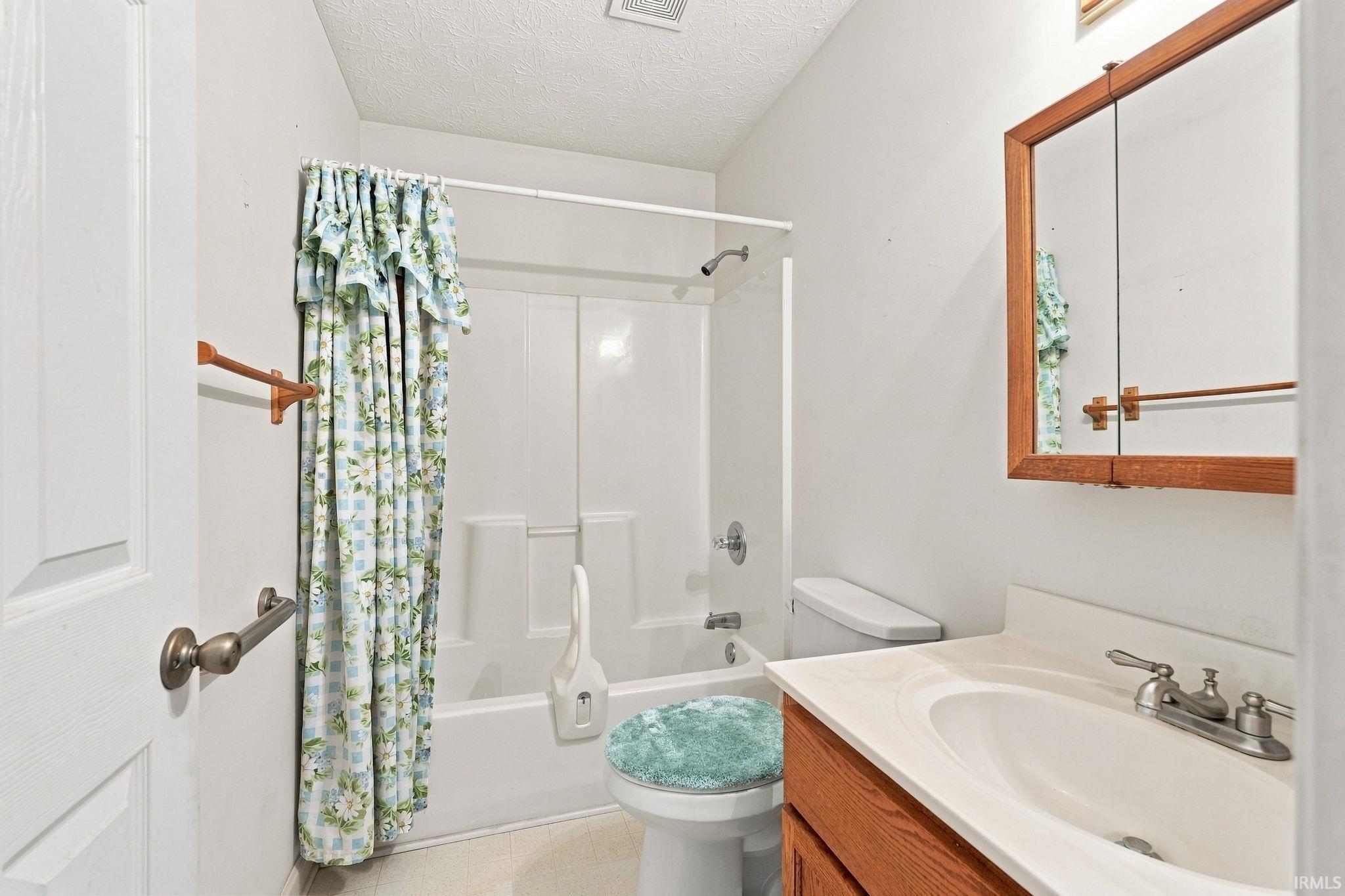 Bathroom featuring a white vanity with integrated sink, chrome faucet, wood-framed medicine cabinet, and a shower/tub combination