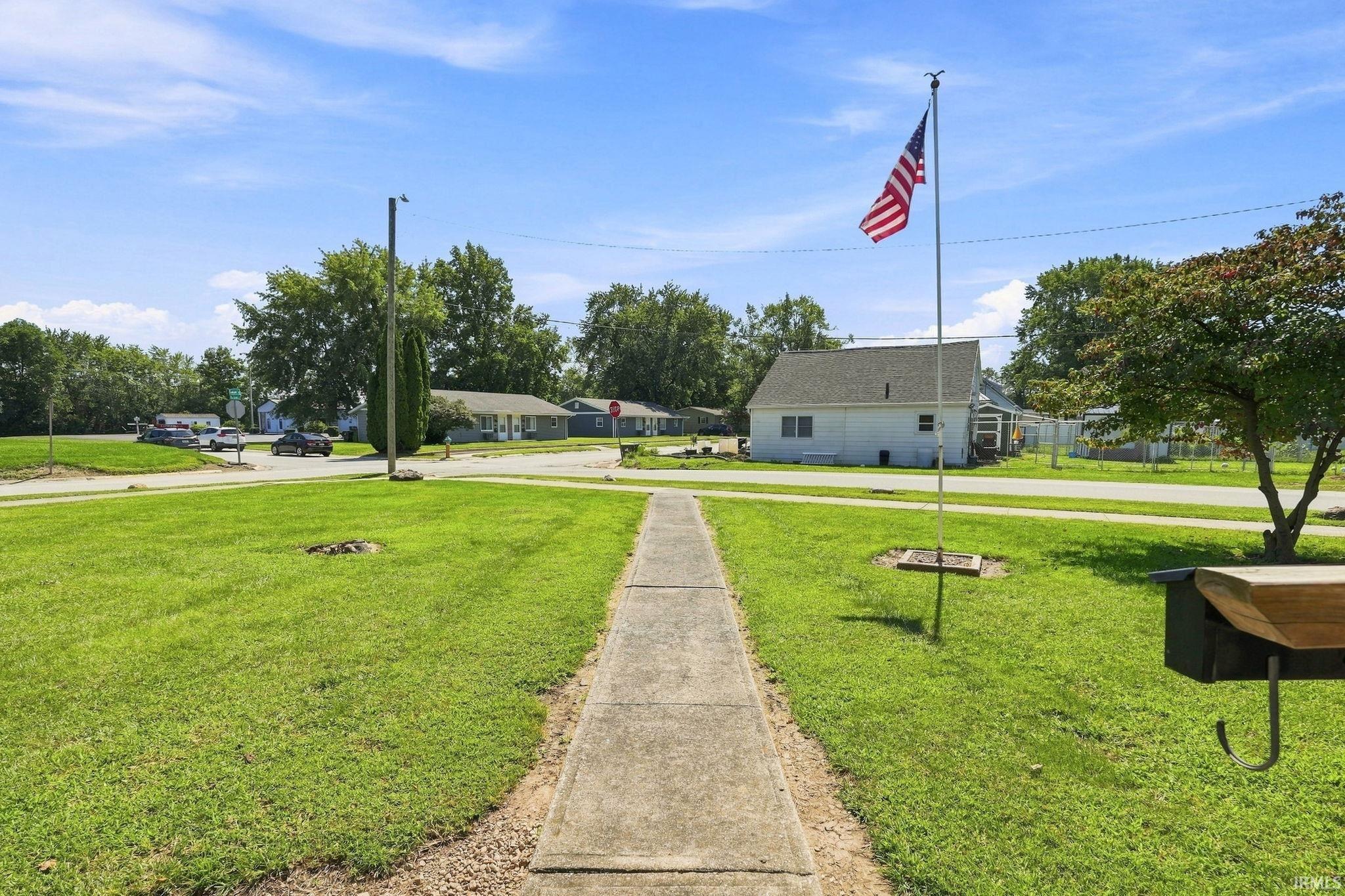 Expansive lawn with a concrete walkway and mature trees