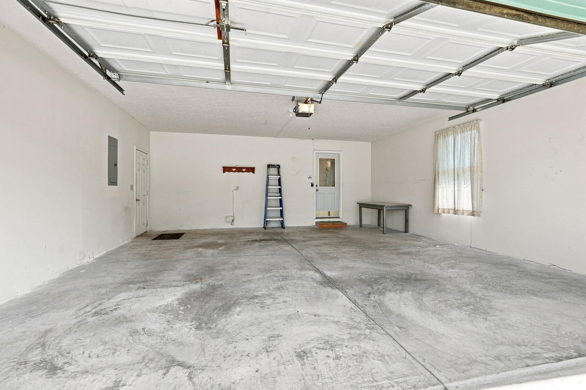 Attached garage with concrete flooring, white walls, and a window with natural light